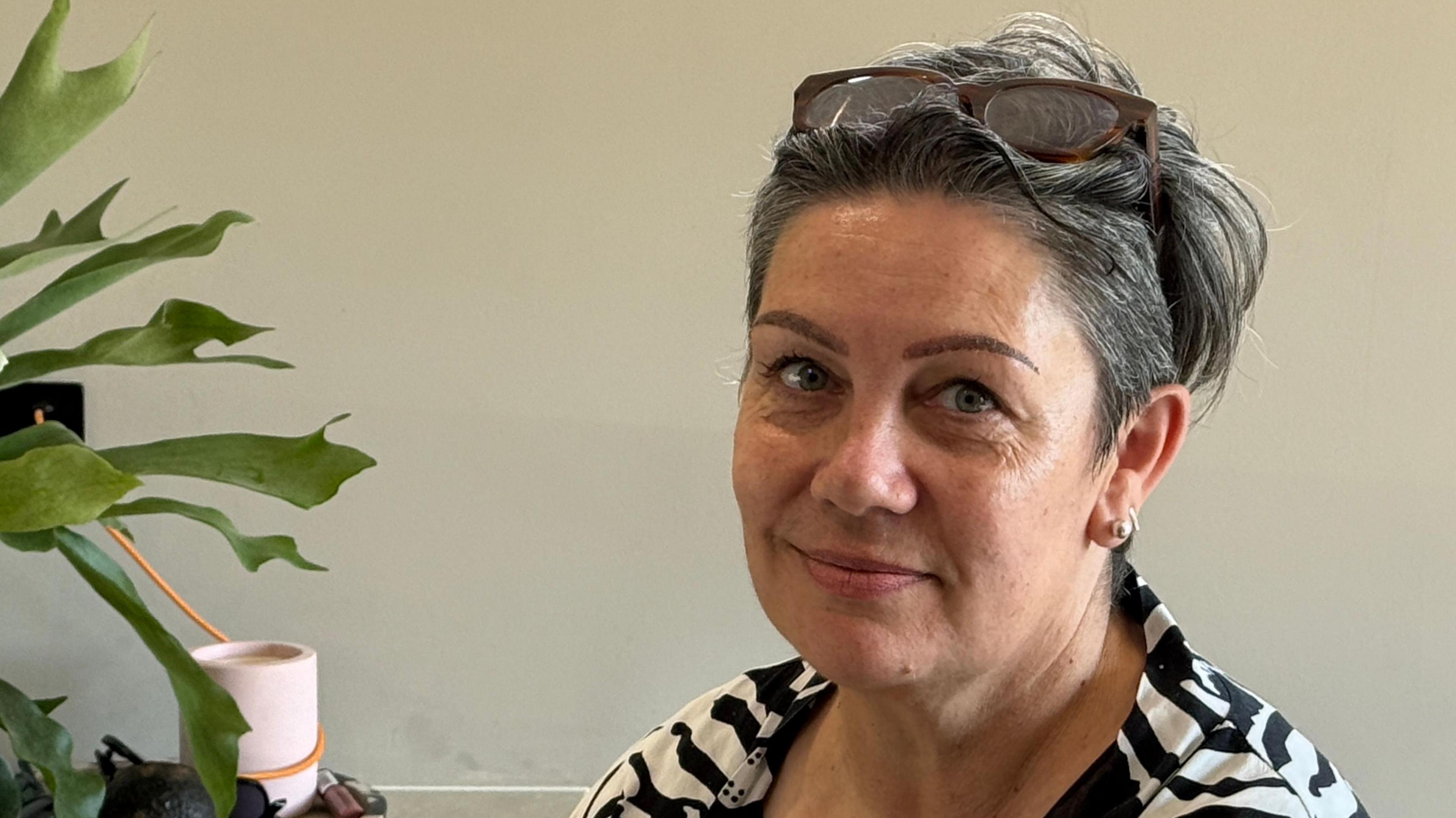 Wendy Bird has short hair with sunglasses on her head. She is wearing a black and white striped T-shirt.