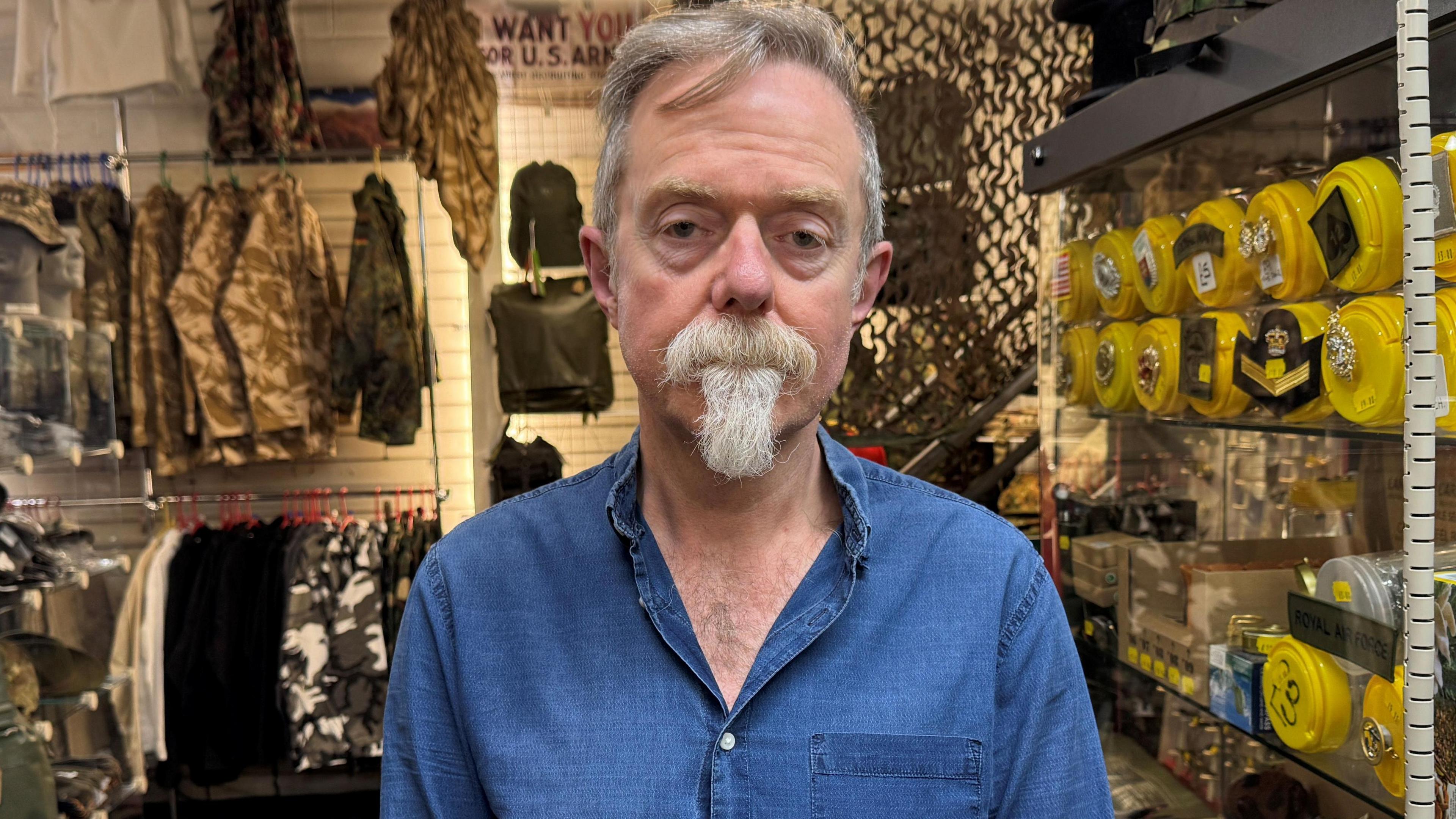 A man with white hair and beard wearing a blue shirt