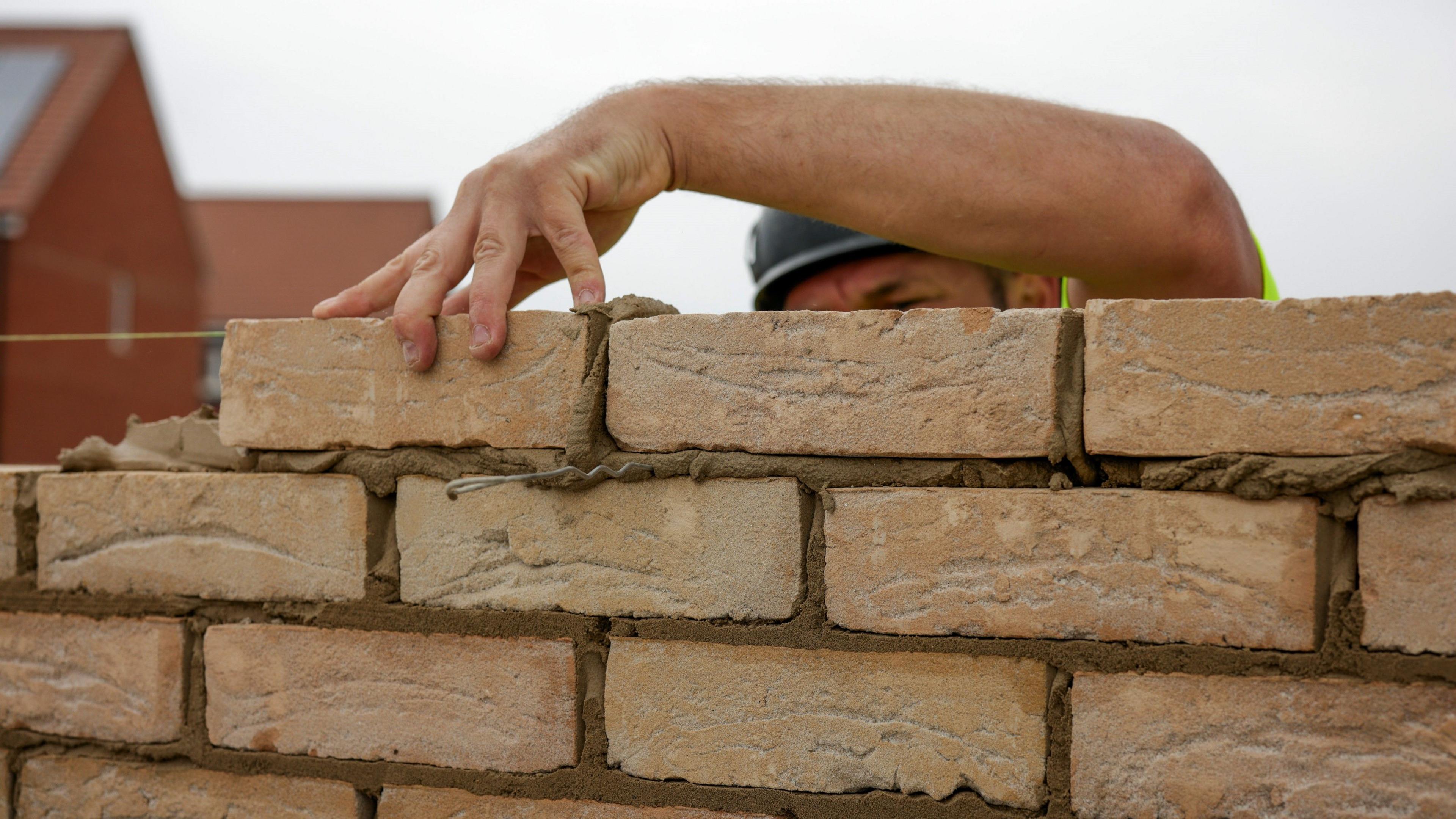 close up of a builder laying bricks on a wall