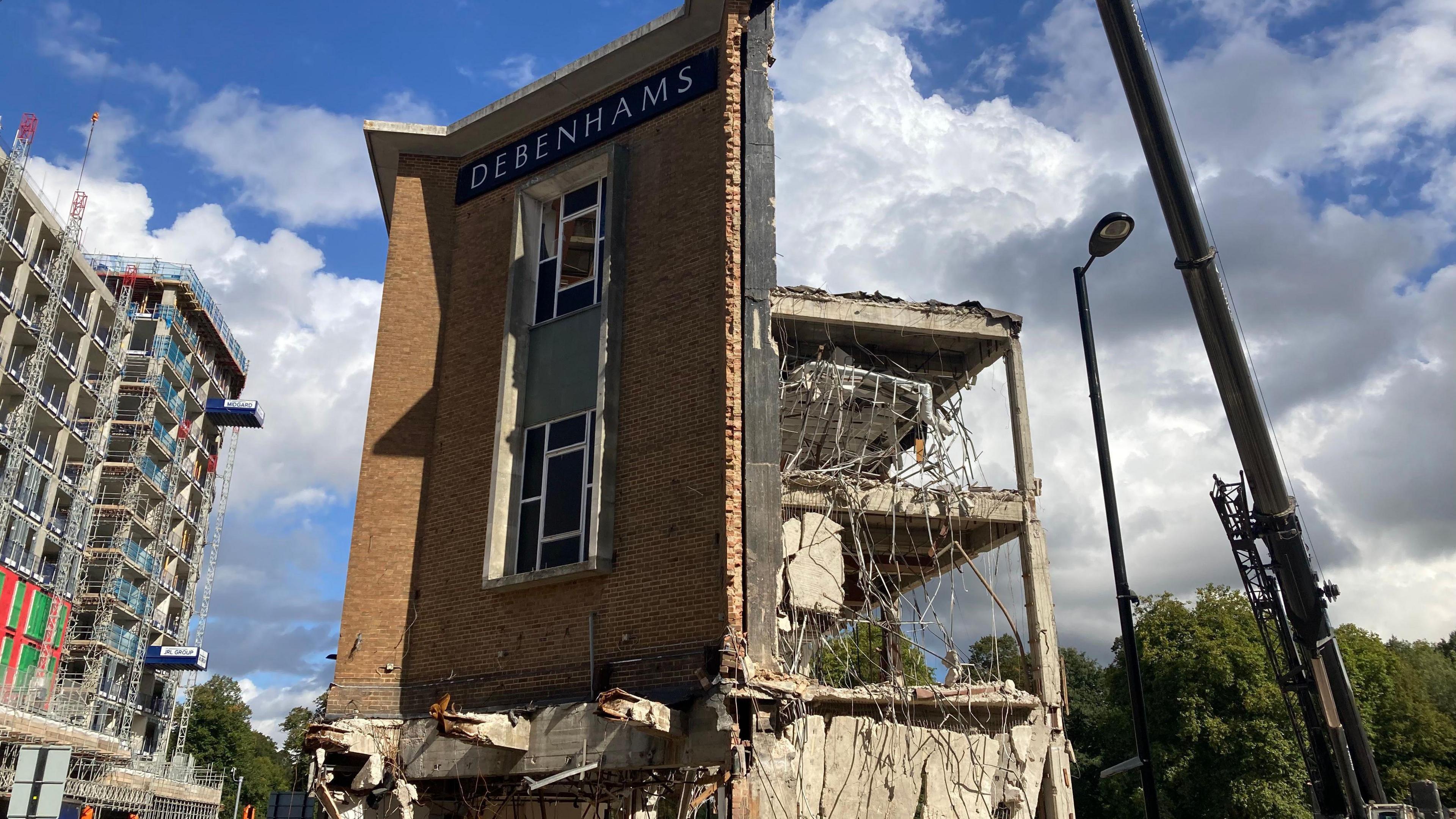 A front facade is all that remains of the former Debenhams store - which also has the store's logo on it. The back of the building is mostly demolished.