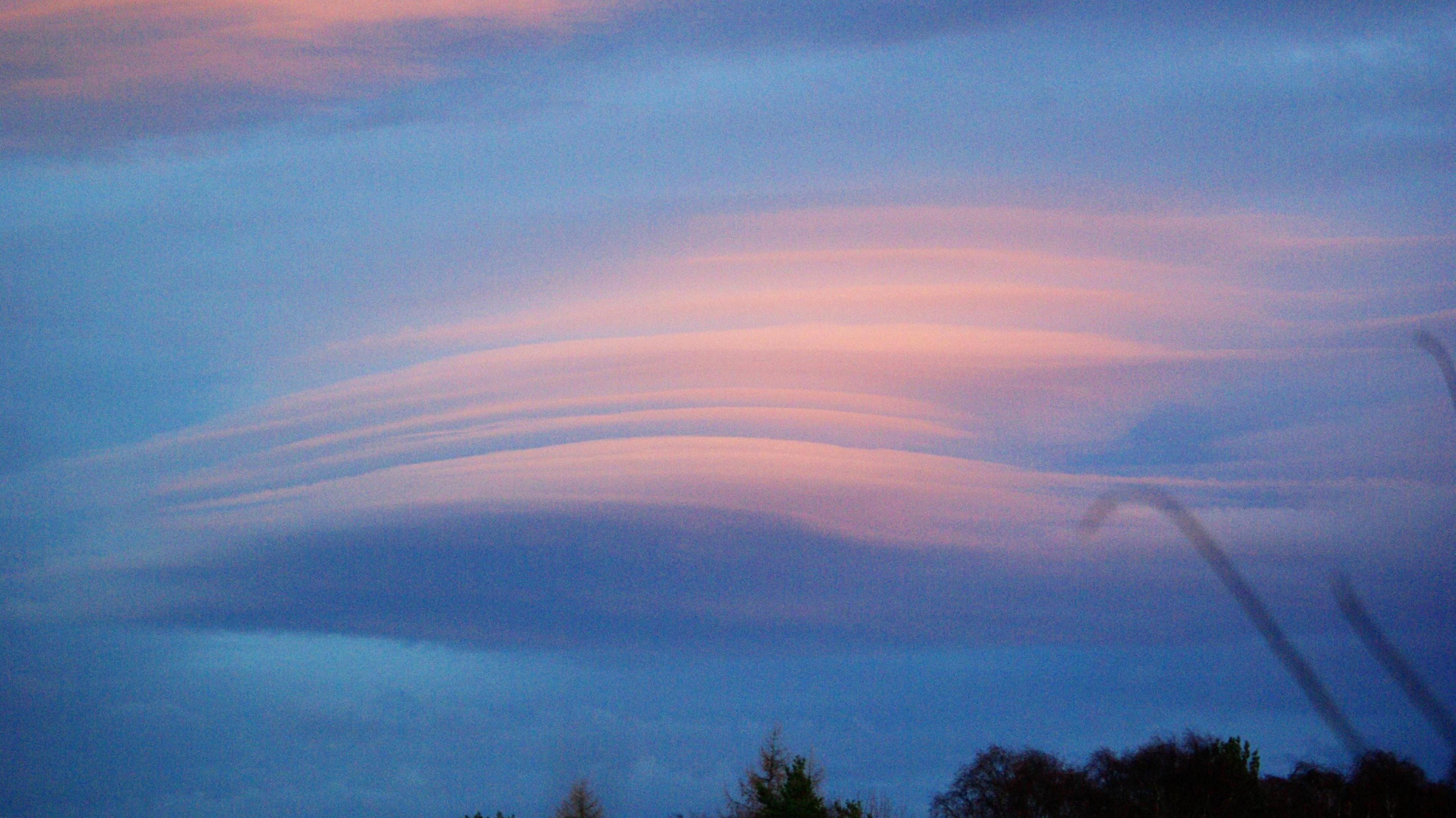 Layers of pinkish clouds stand out against darker clouds behind them