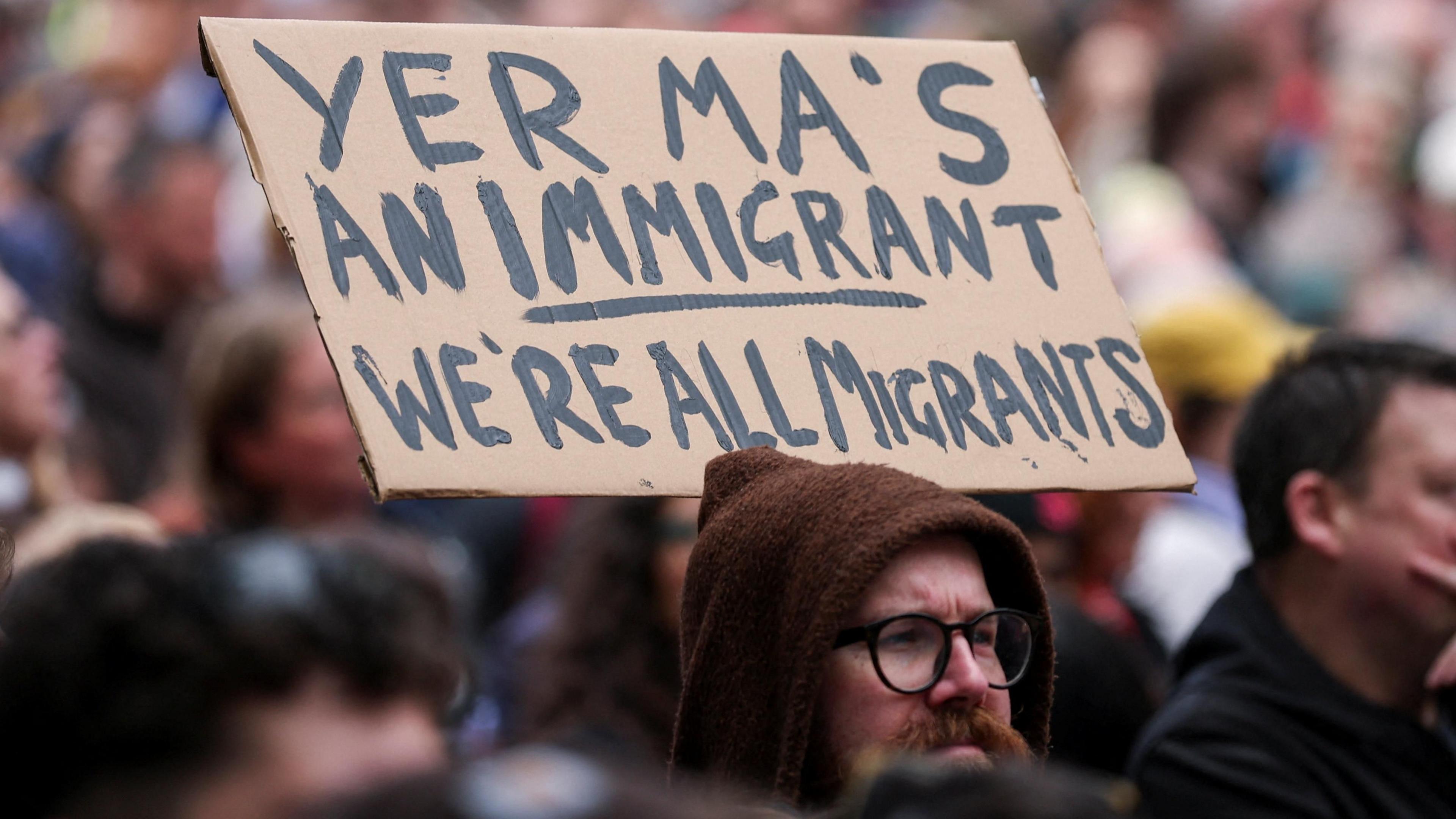 A person holds a placard saying Yer ma's an immigrant. We're all immigrants uring a 'United Against Racism' rally after days of anti-immigration violence, following a knife attack on June 8, which left a man seriously injured and prompted police to declare a critical incident, in Belfast, Northern Ireland, June 13, 2026. REUTERS/Isabel Infantes's an immigrant. We're all immigrants uring a 'United Against Racism' rally after days of anti-immigration violence, following a knife attack on June 8, which left a man seriously injured and prompted police to declare a critical incident, in Belfast, Northern Ireland, June 13, 2026. REUTERS/Isabel Infantes