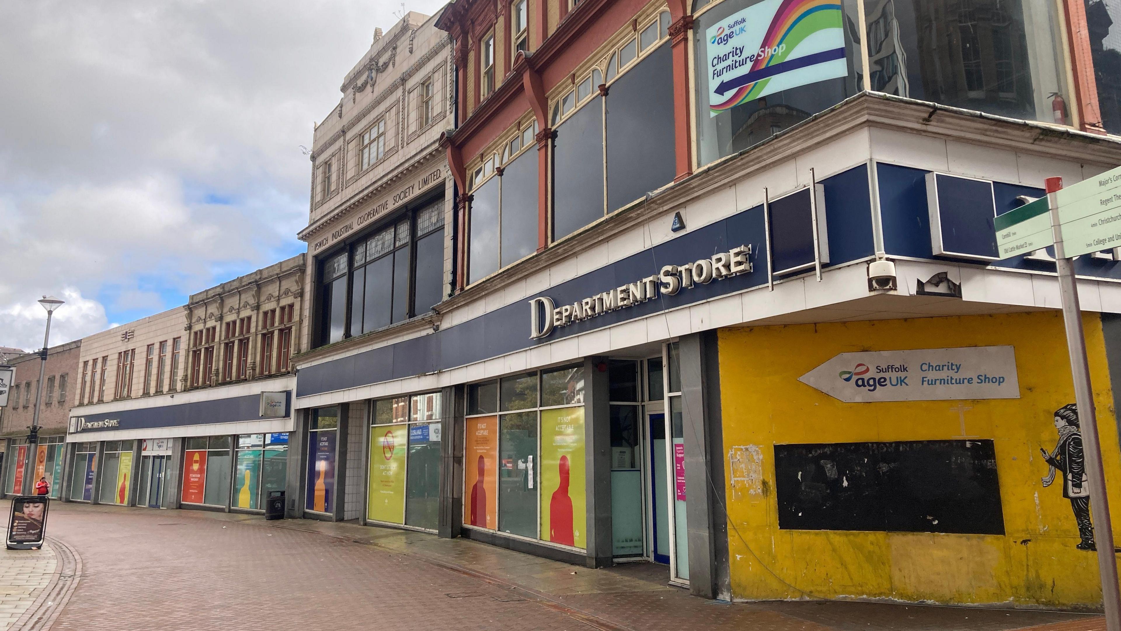 A photo of Ipswich High Street and an empty department store which has been boarded up. The words 'Department Store' remain on the building which looks run down. 