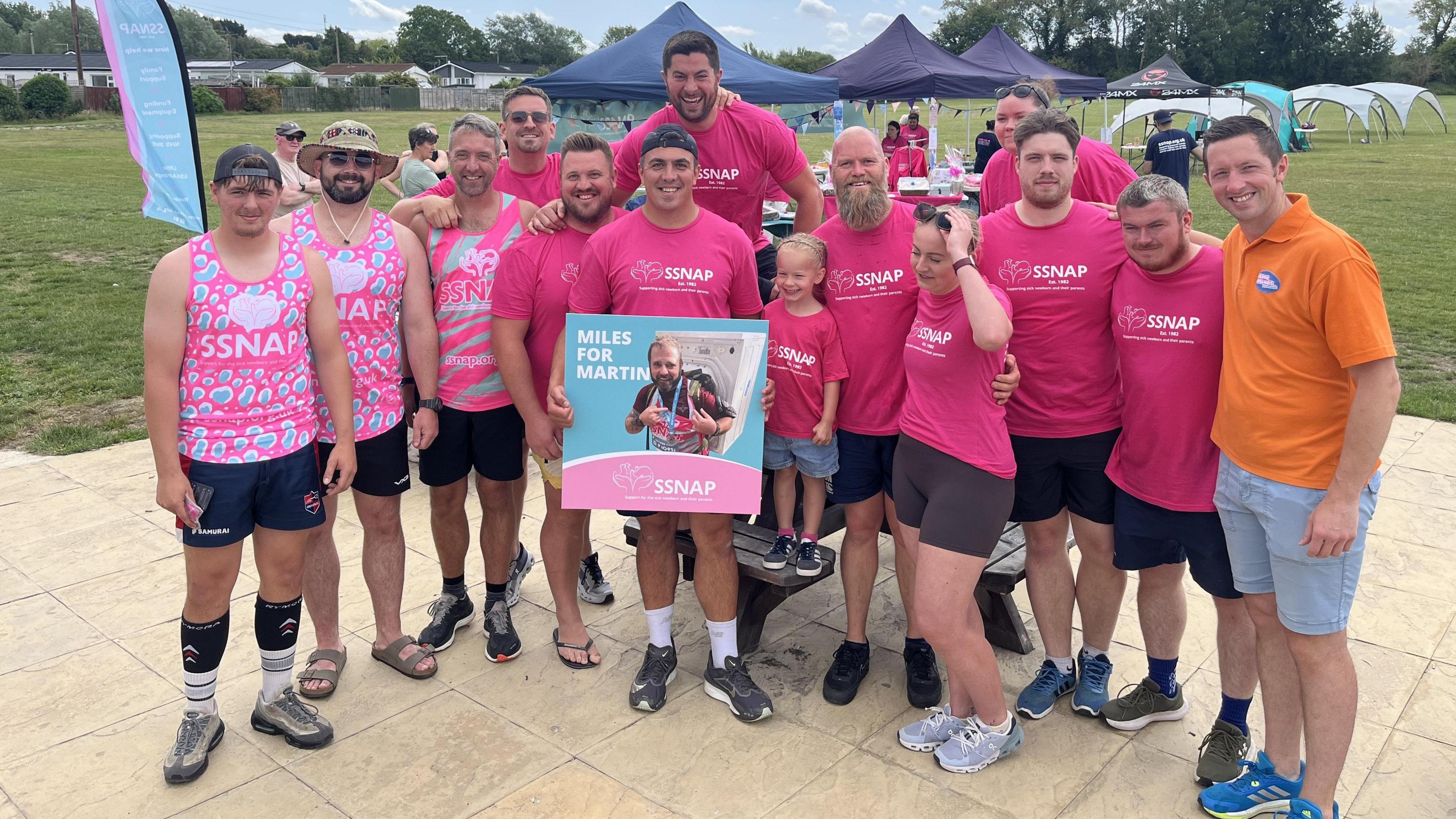 The fundraisers gather for a group photo. They are holding up a placard with Martin on it, and it says 'Miles for Martin'.