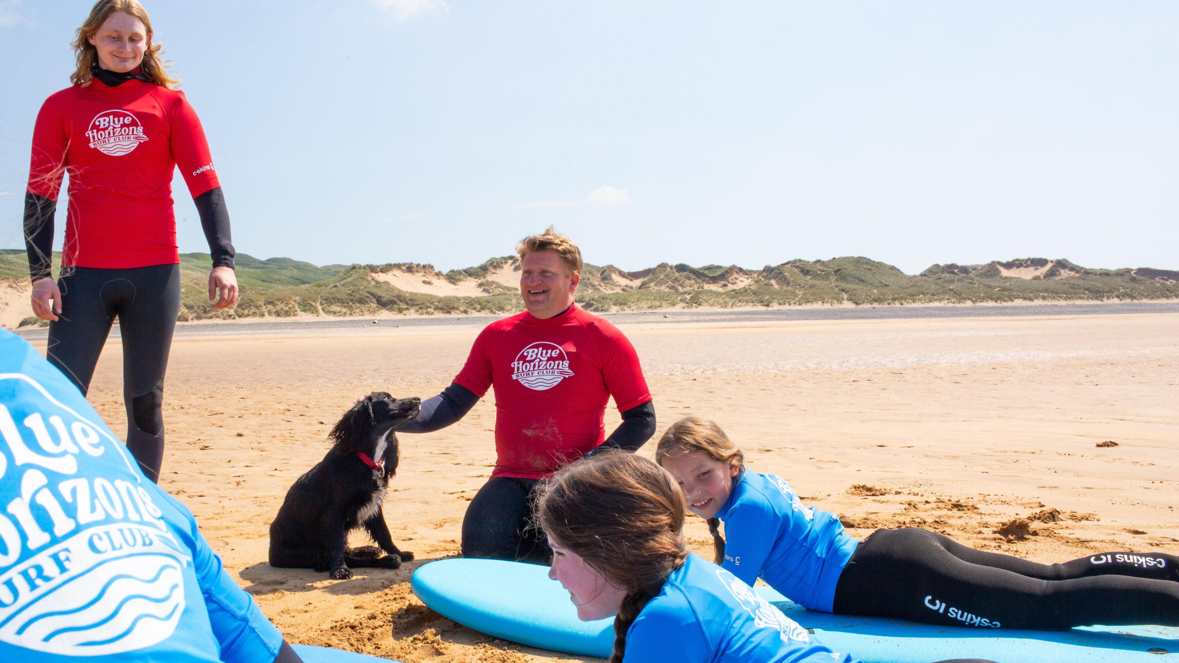 Ariel, the formerly six-legged dog, with members of the surf club on the beach