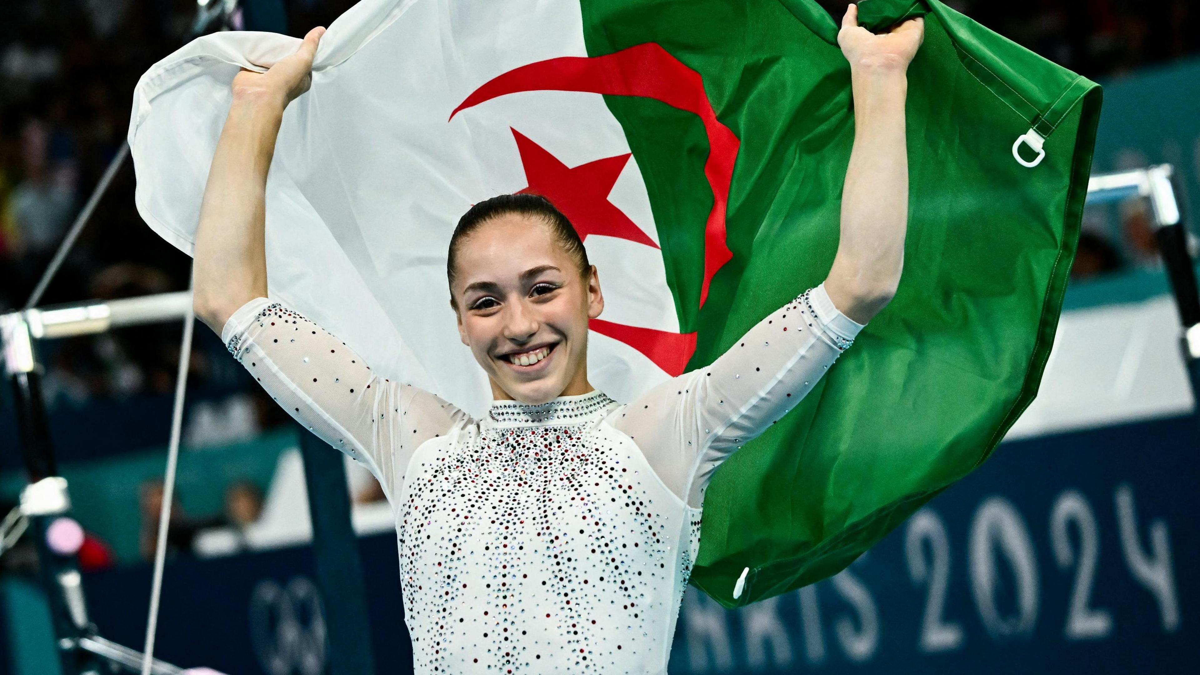 Kaylia Nemour celebrates with an Algerian flag after winning the uneven bars final at Paris 2024