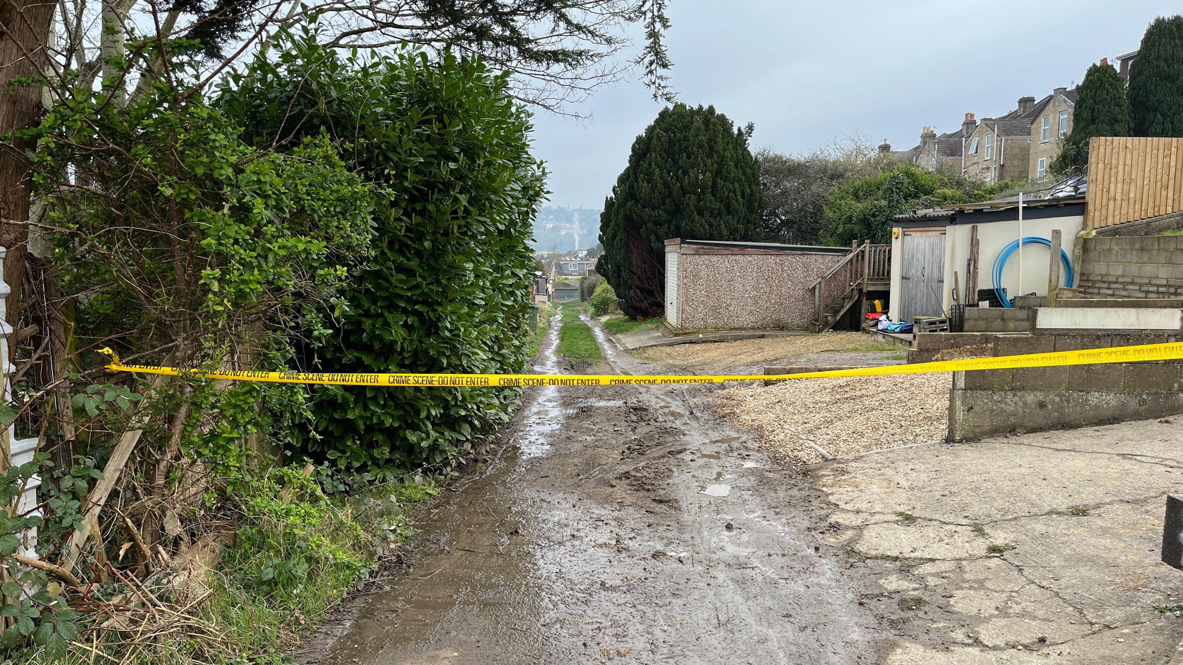 Image of the crime scene in Dransfield Way, Bath with yellow police tape across the alleyway