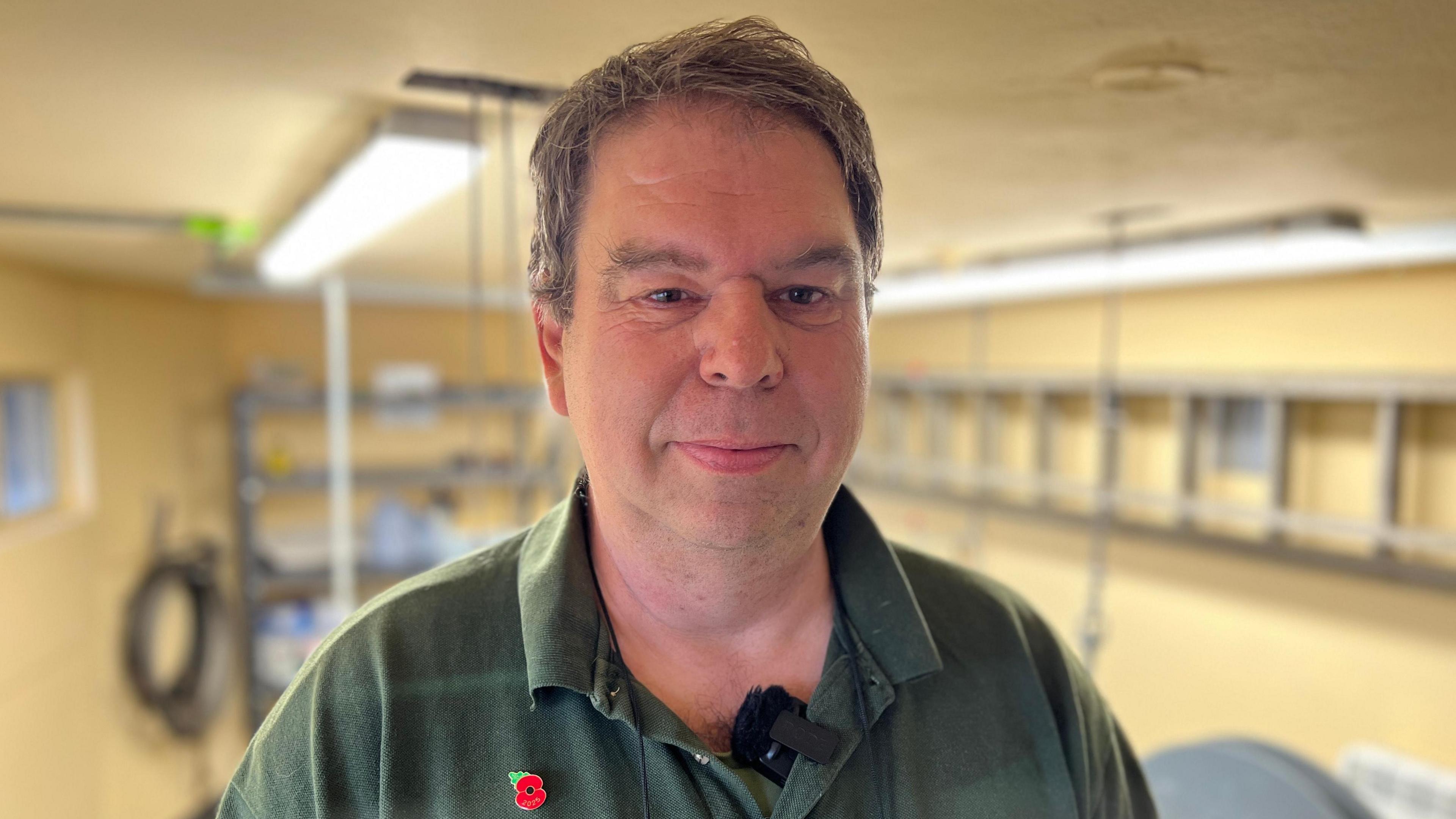 Wayne Francis standing next to part of the clock mechanism