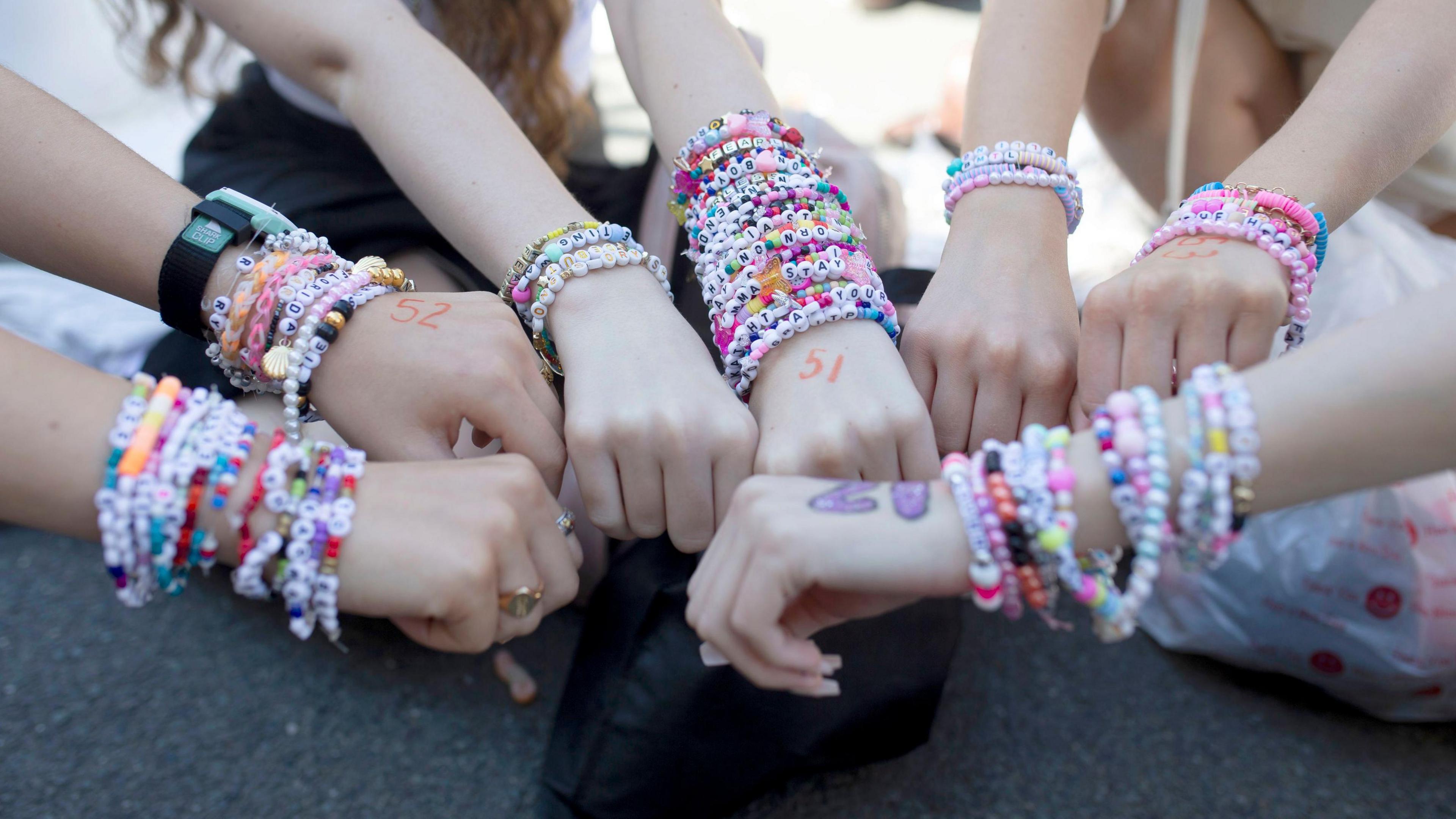 Taylor Swift fans all wearing friendship bracelets at an Eras Tour concert.