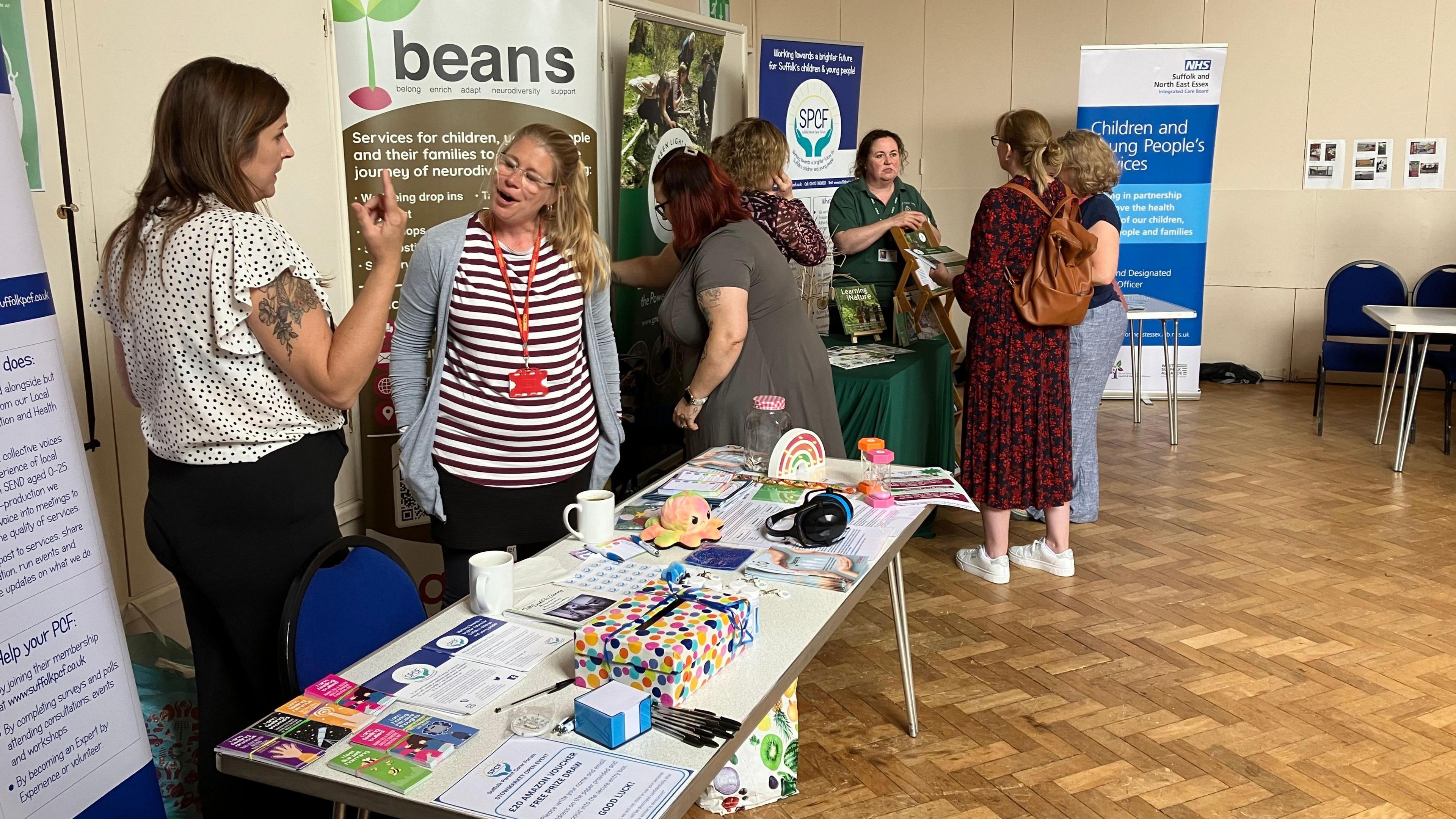 A group of people talking behind tables at the open forum event in Stowmarket 