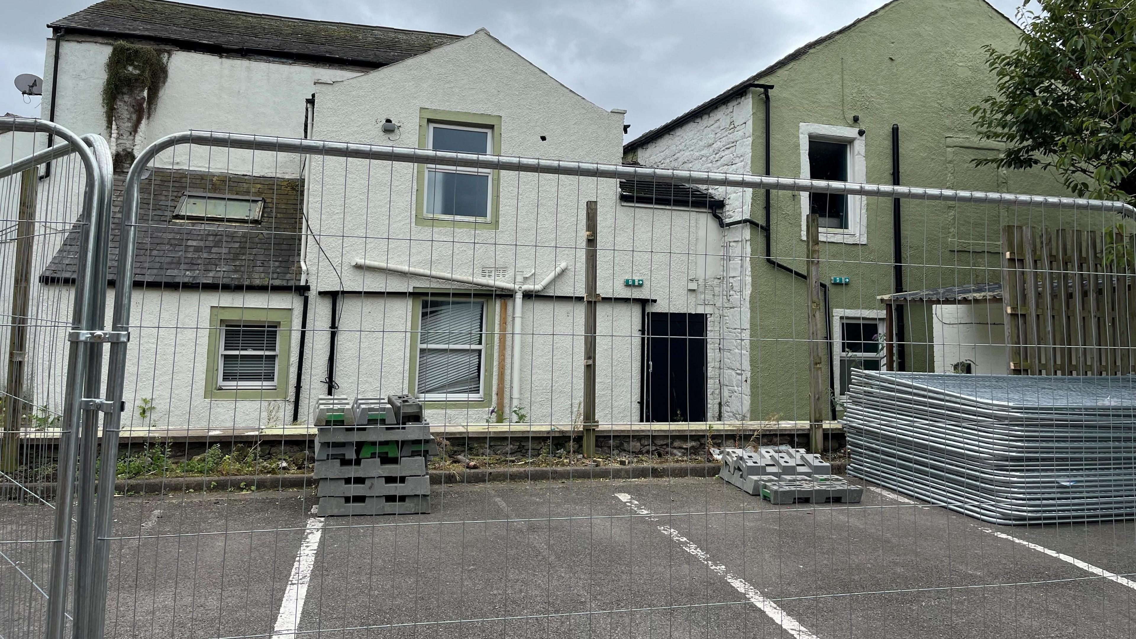 A picture of a fenced-off area to the side of the former Henry's Bar in Workington