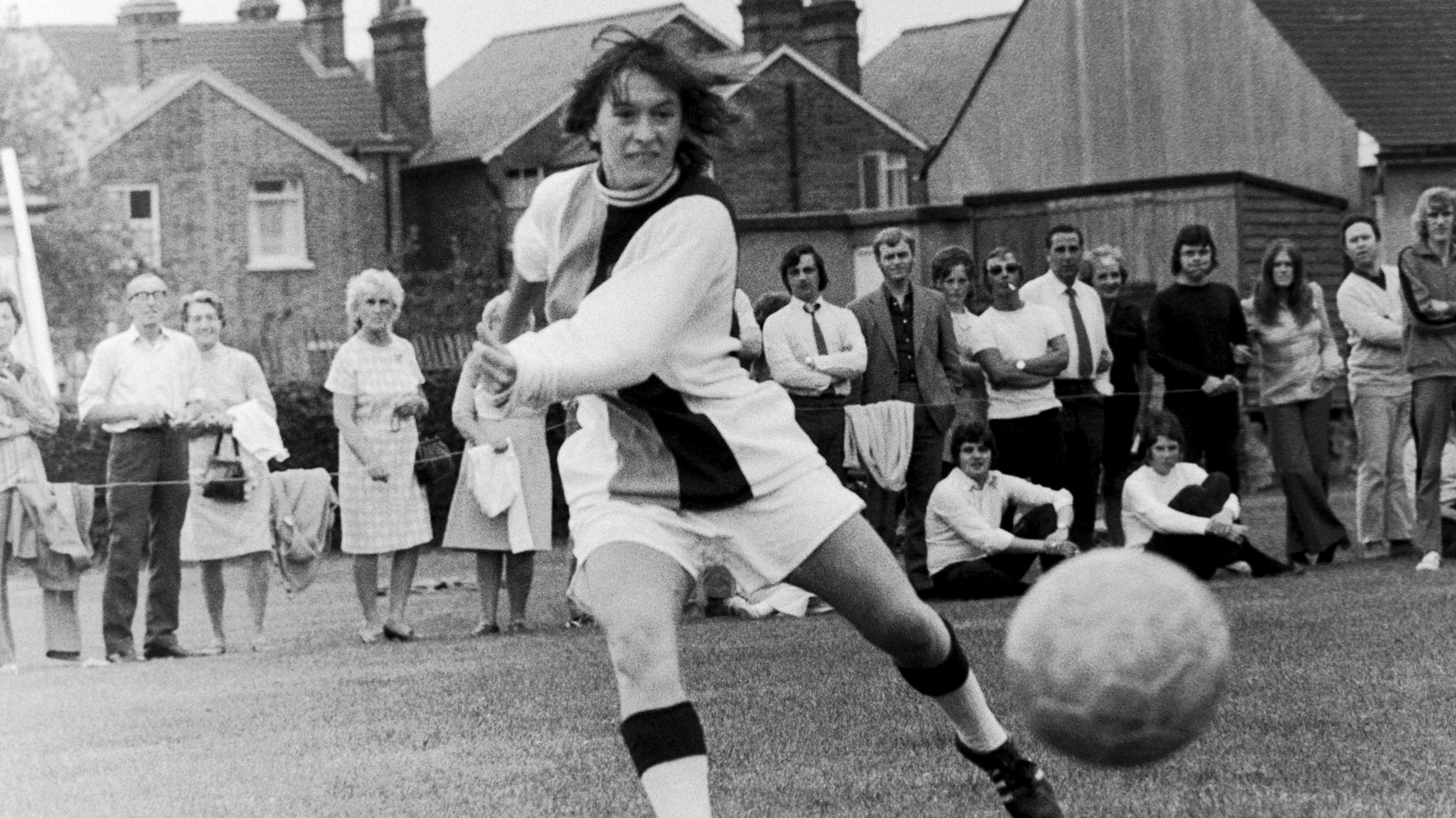 Crystal Palace ladies player in play with the ball coming towards her with spectators standing on the grass behind her watching the match