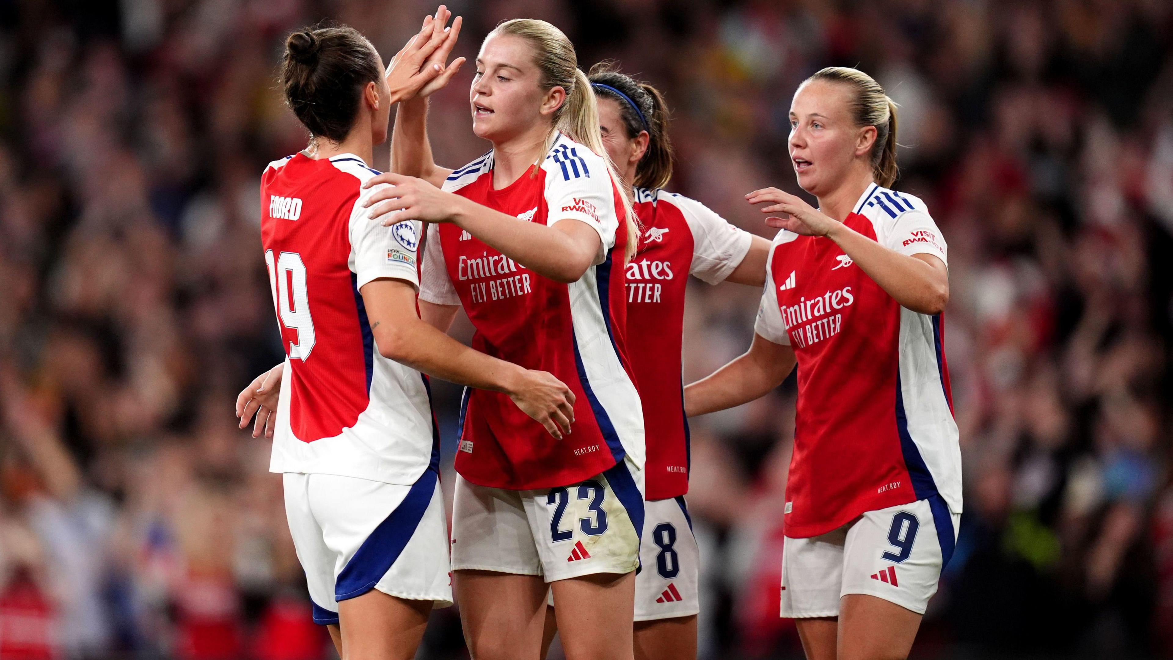 Arsenal players including Beth Mead and Alessia Russo huddle to celebrate a goal.