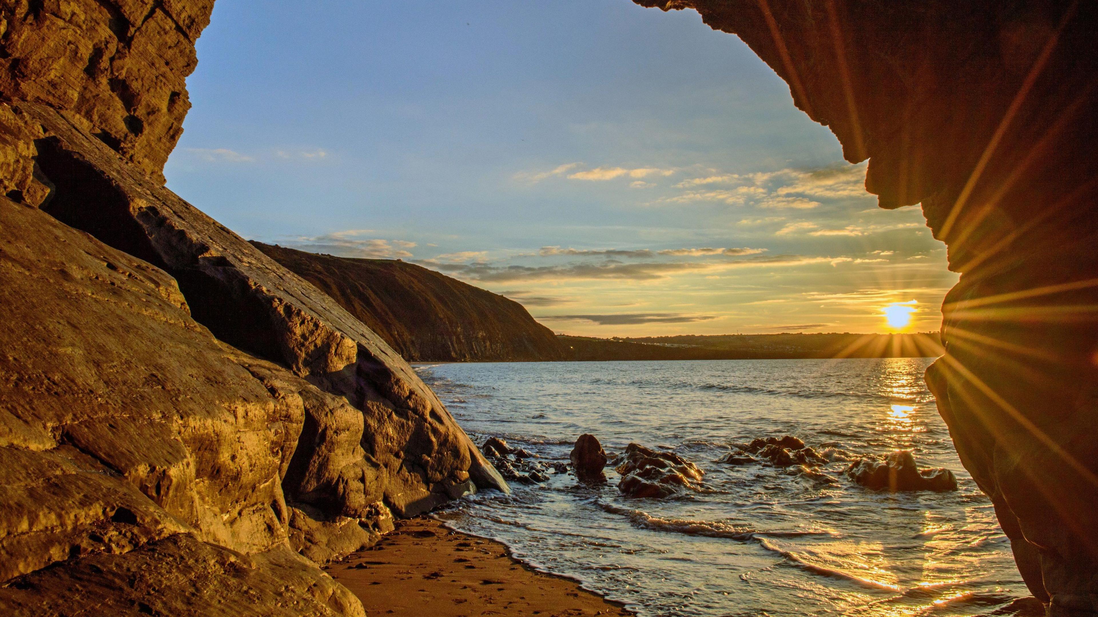 A view fo the beach at Penbryn at sunset through the middle of a rock formation