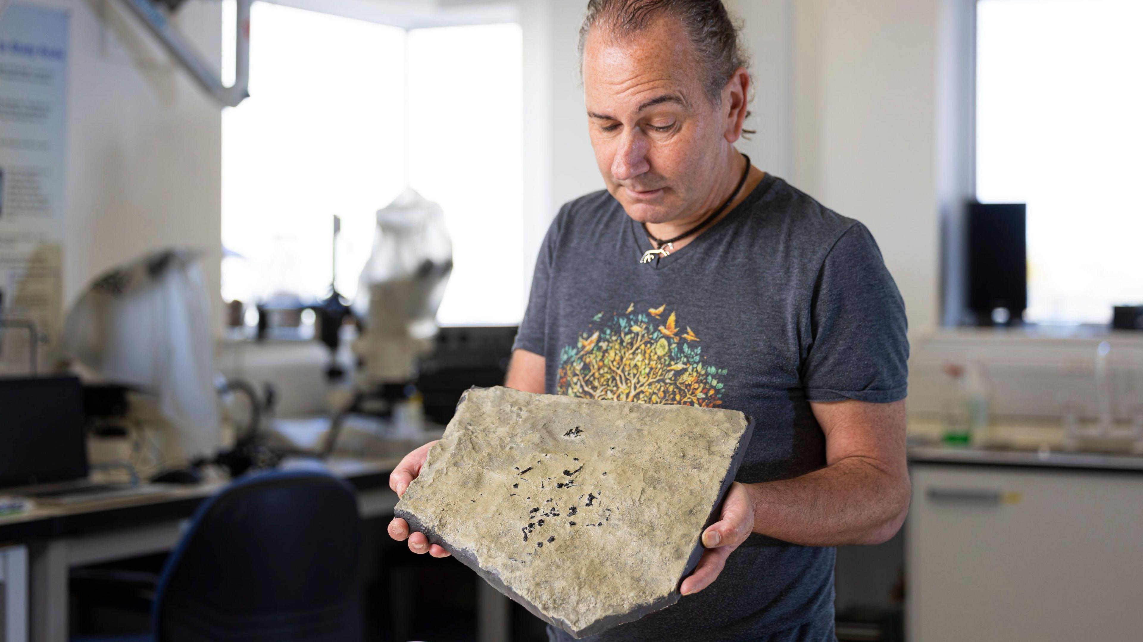Dr Stig Walsh holding a cast of the Breugnathair elgolensis fossil