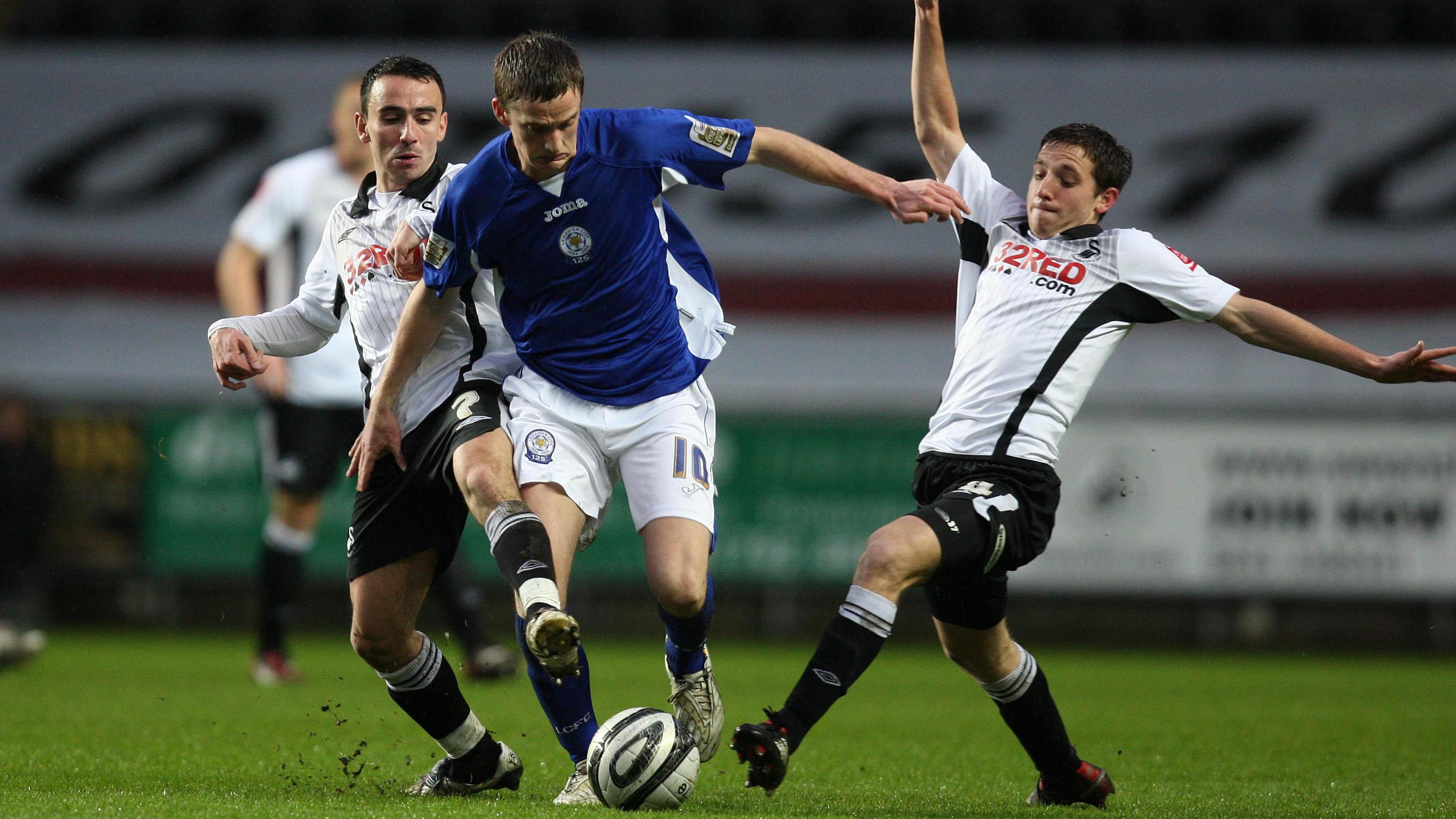 Leicester's Andy King is tackled by Swansea's Leon Britton (l) and Joe Allen (r) during a Championship game in January 2010