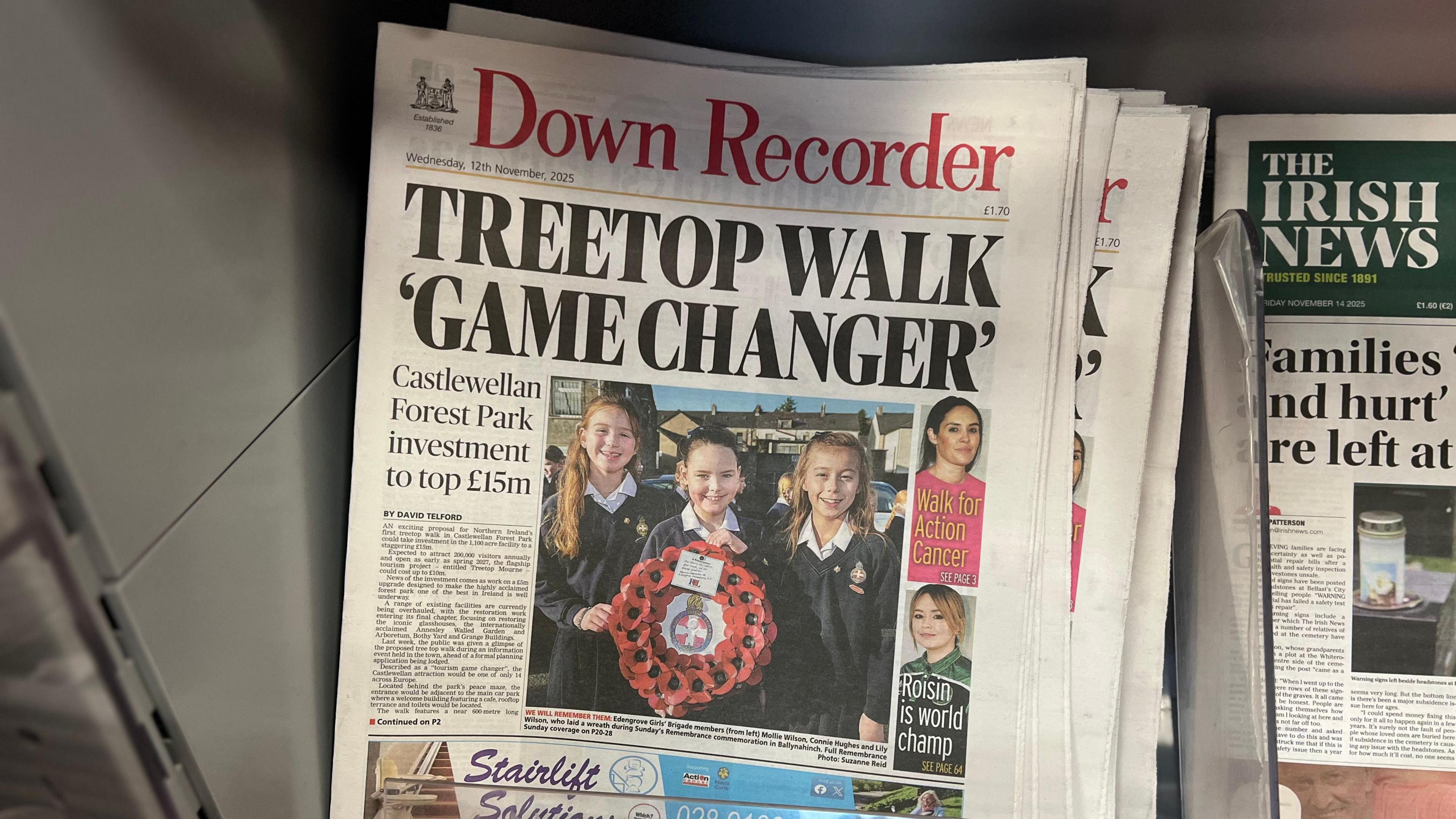 A pile of Down Recorder newspapers are on top of each other. The headline is Treetop Walk Gamechanger. There a photo of young people with a poppy wreath on the front page.