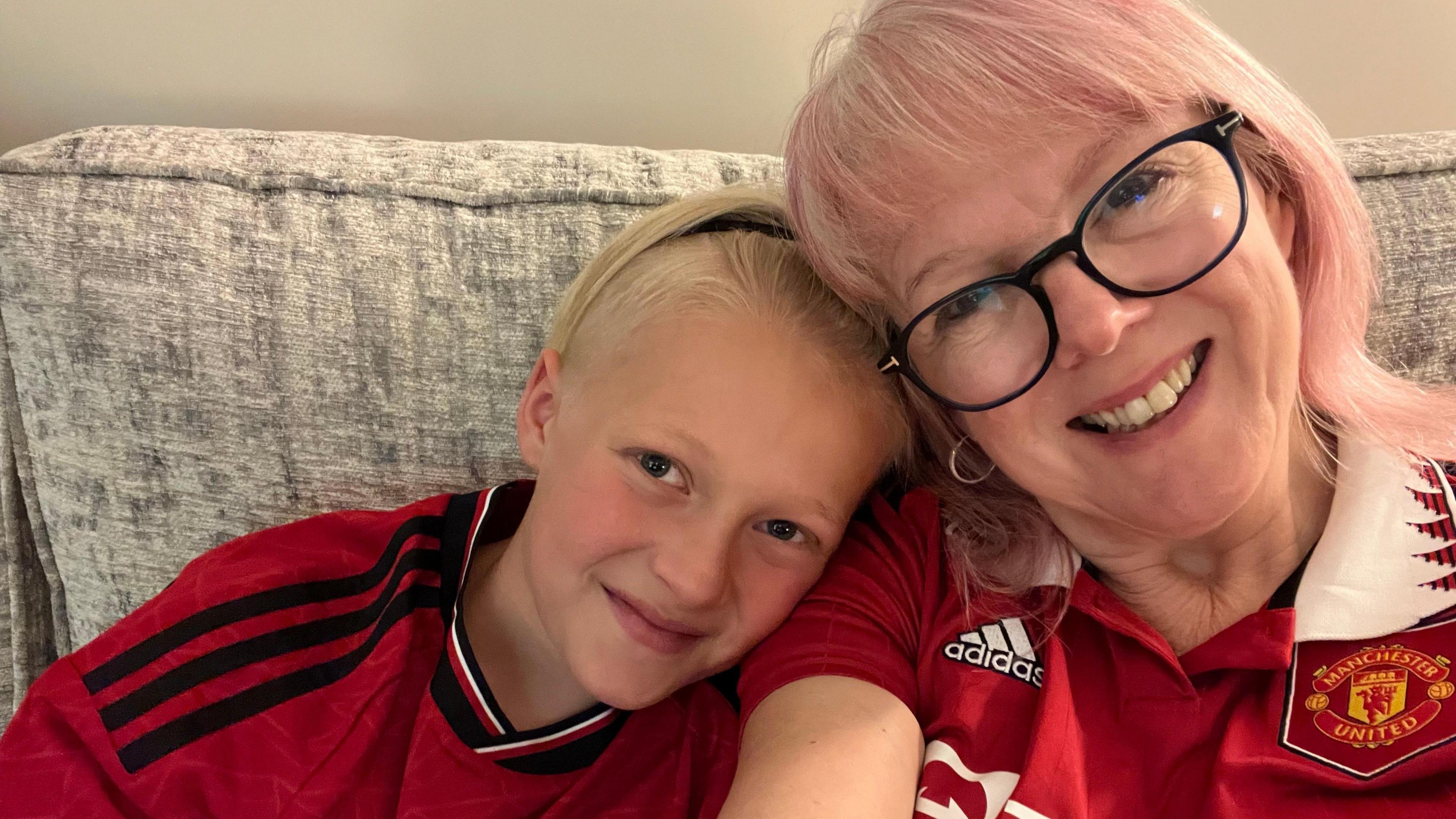 A grandmother poses for a selfie with her grandson, both dressed in Manchester United shirts