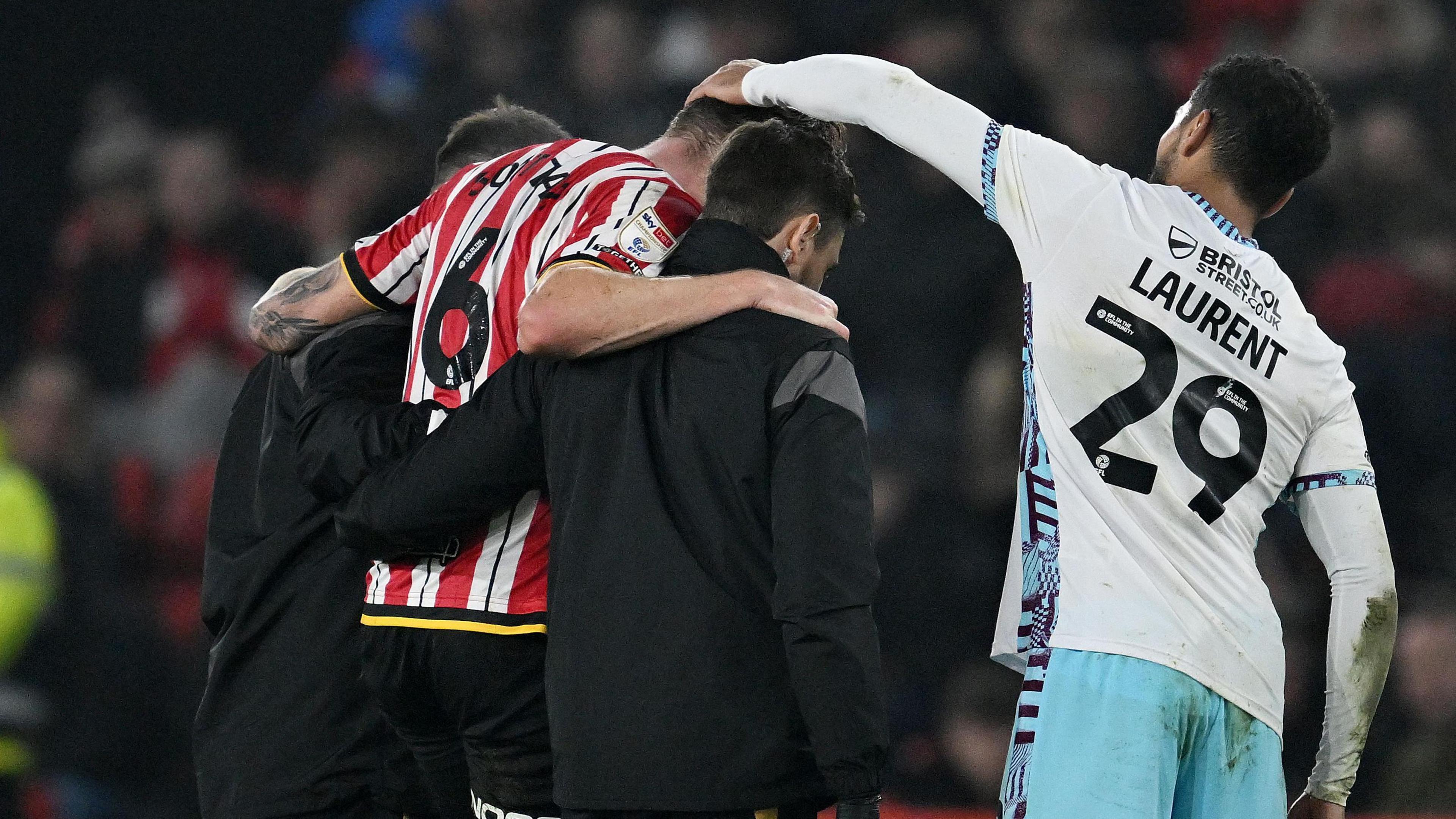 Sheffield United defender Harry Souttar is helped from the pitch by staff, while Burnley player Josh Laurent offers a pat of consolation