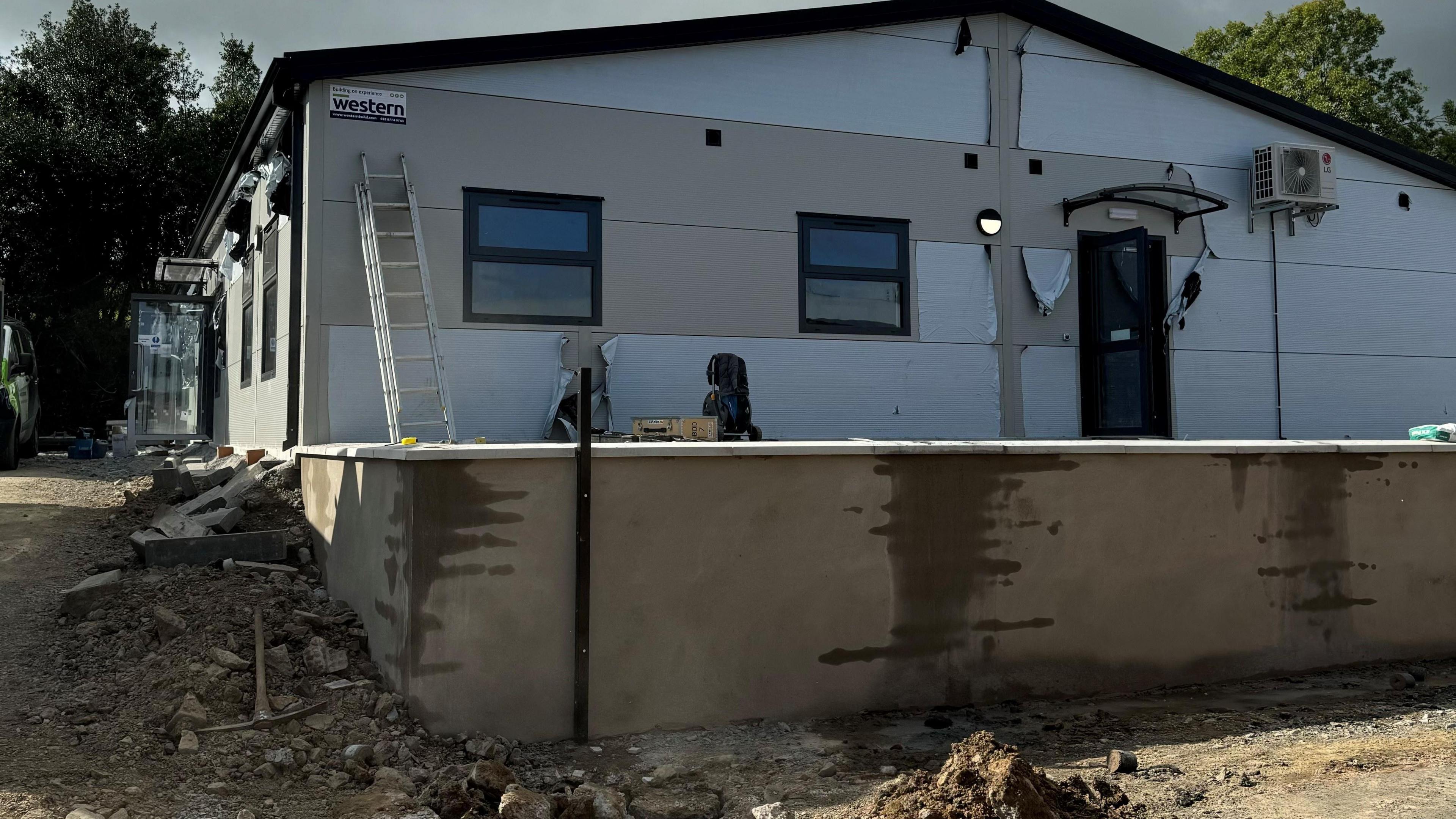 An unfinished building at Oakwood School in Saintfield with a ladder leaning against it. Rubble on the ground around the building.