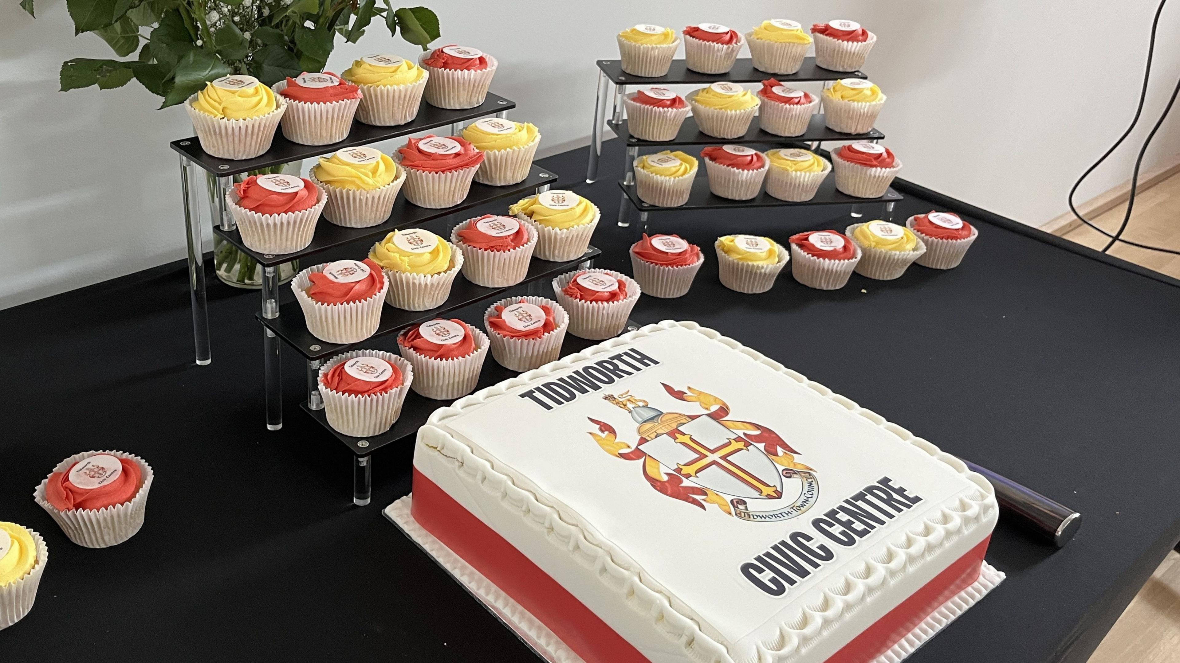 Cake with the Tidworth coat of arms and Tidworth Civic Centre iced onto the top of the cake, surrounded by cup cakes