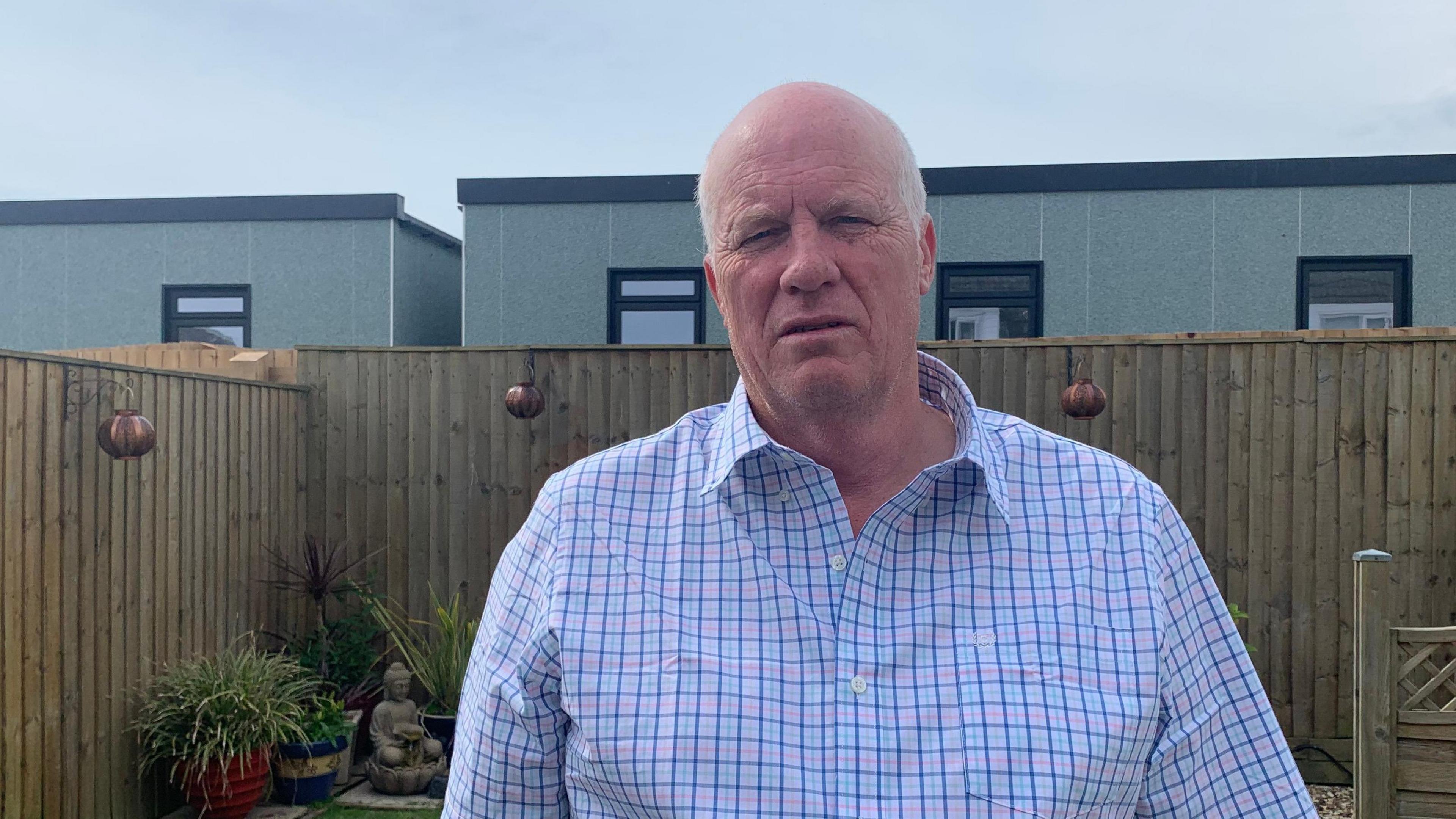 Resident, Dave Thomas, standing in his garden with new temporary homes built at the back of it