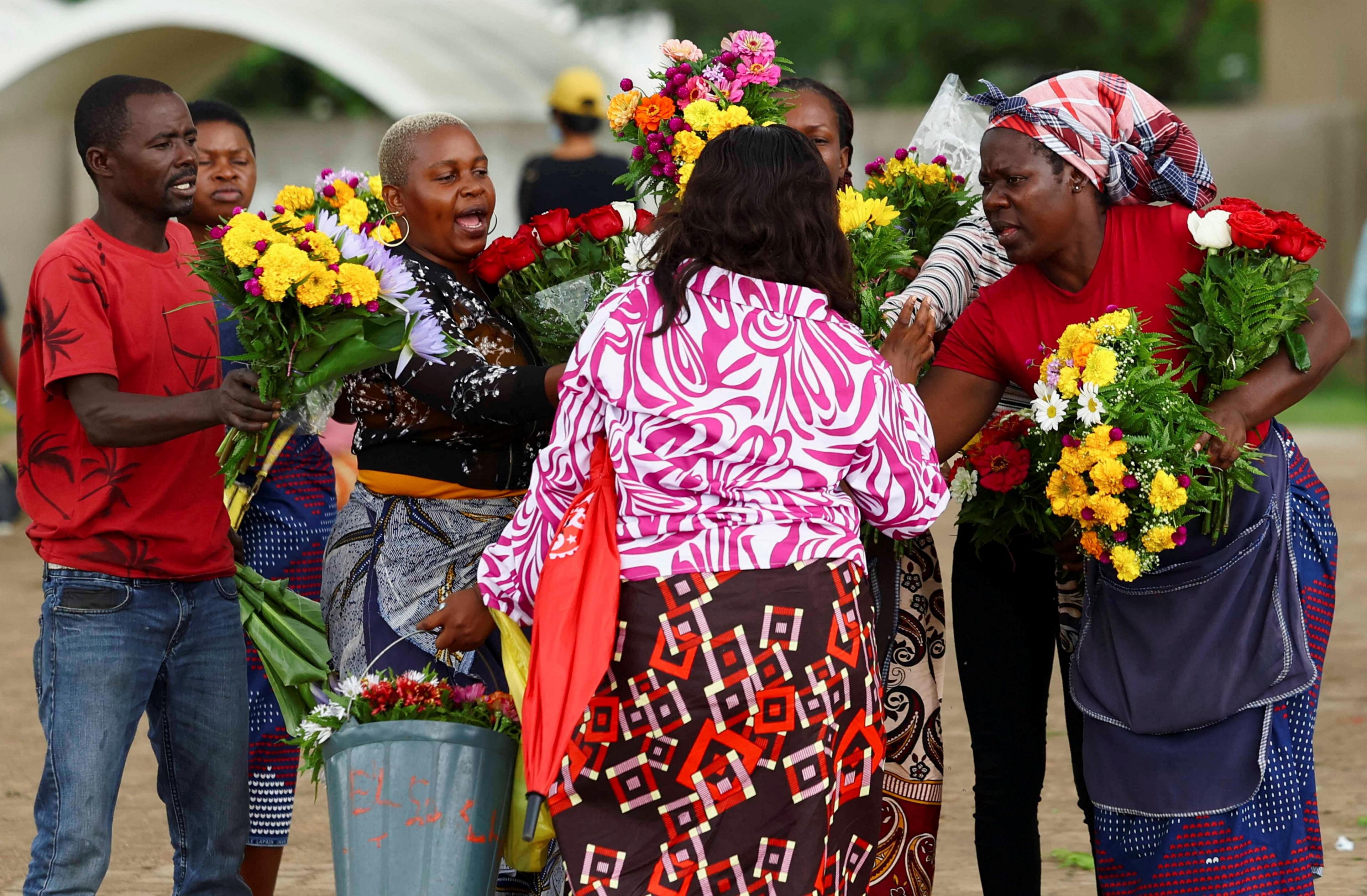 Flower vendors sell to a mourner arriving for the funeral of Hilario Benjamin Dima in Maputo.