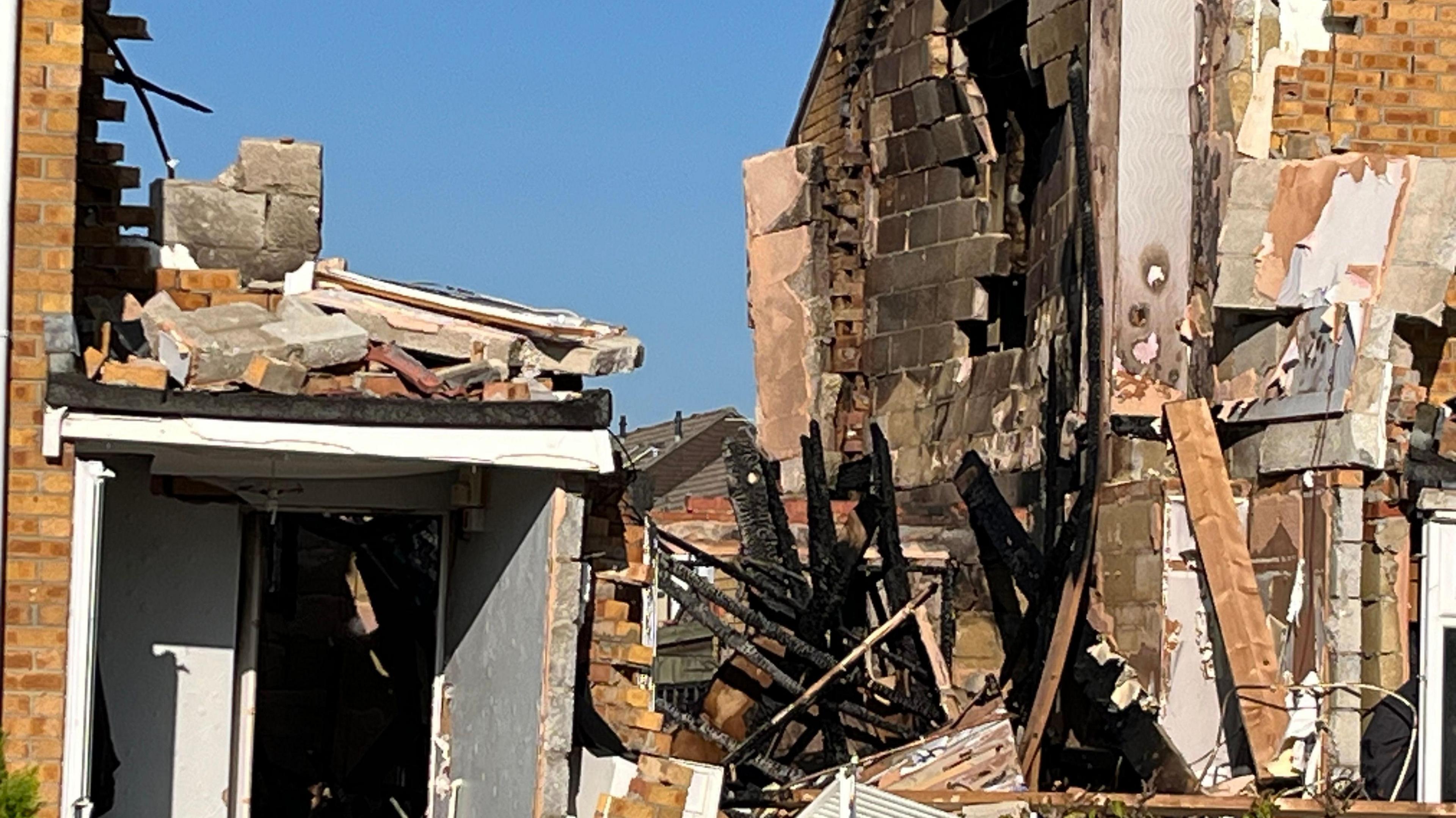 A close up of the property where a suspected gas explosion took place. The neighbouring house has suffered damage too, with a hole in the side of the building. There is debris on the floor between both houses.