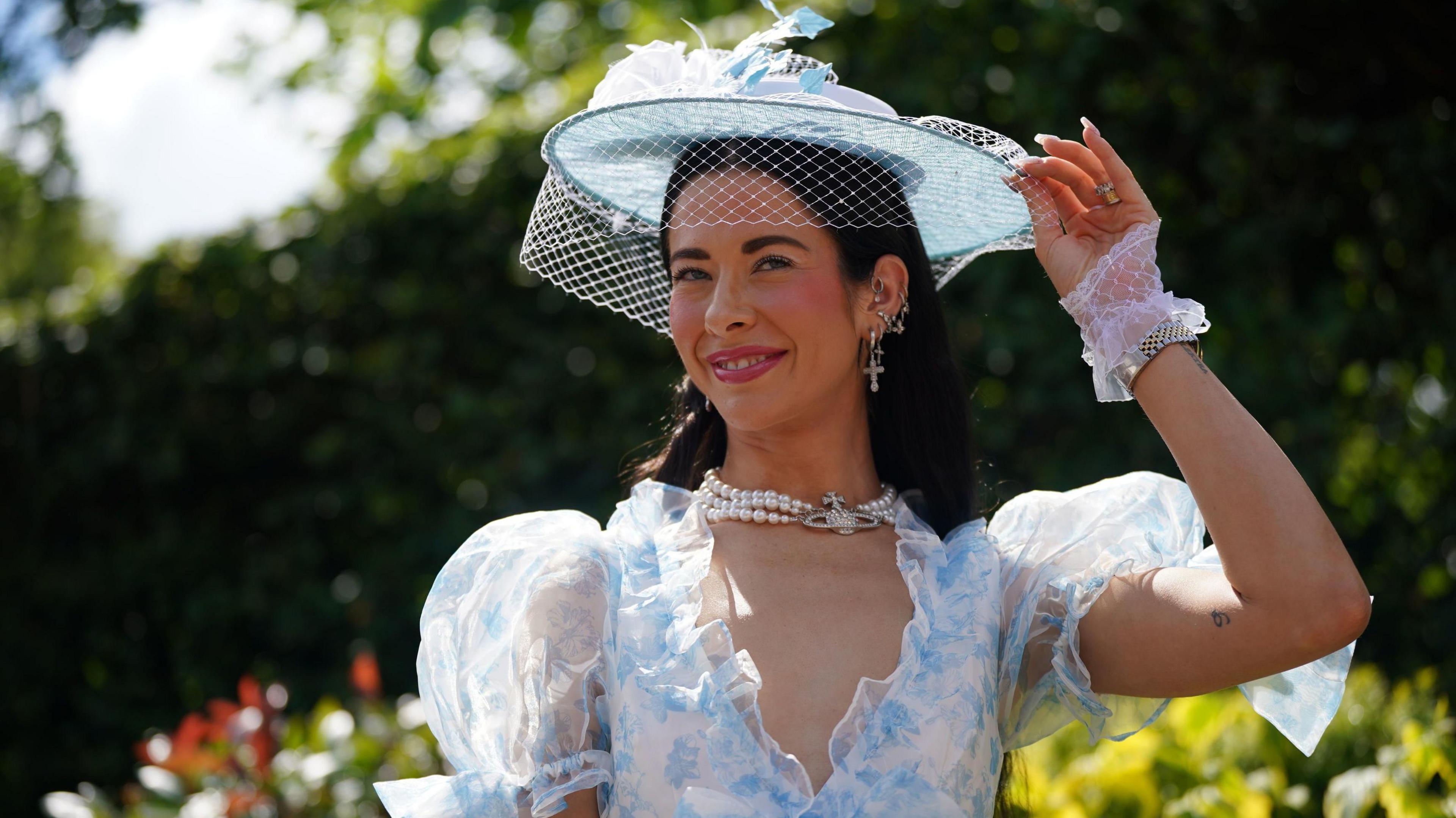 Woman wears pale blue white brimmed headpiece with blue and white floral ruffled dress