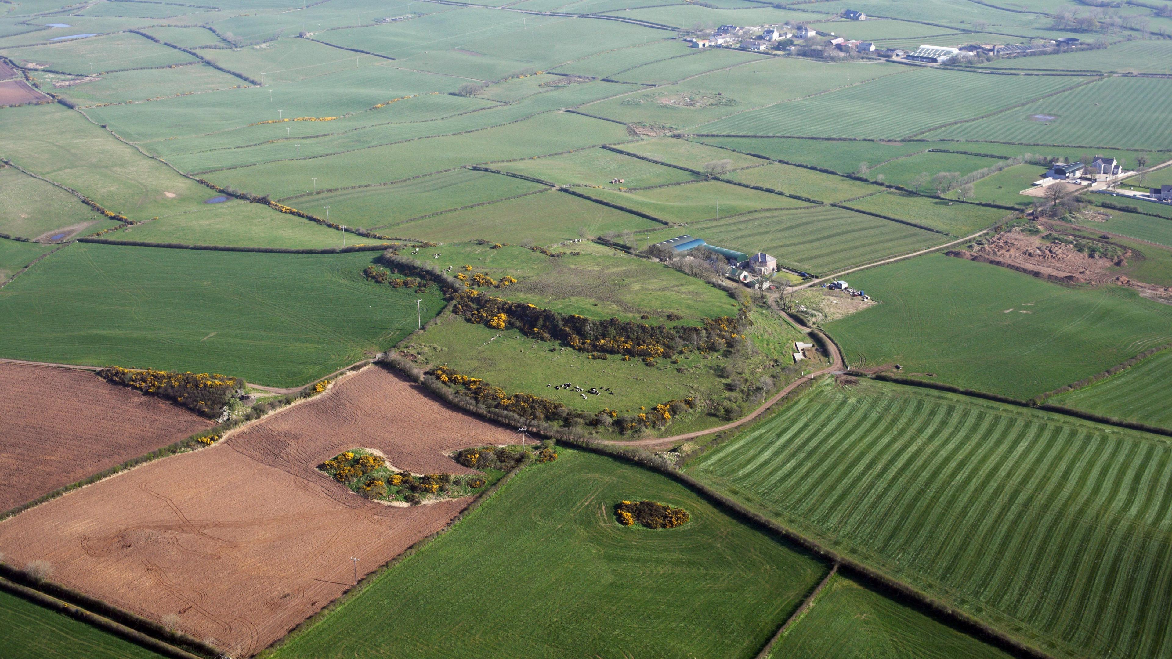 A birds eye view of the fort. It's surrounded by fields. Some houses are in the distance.
