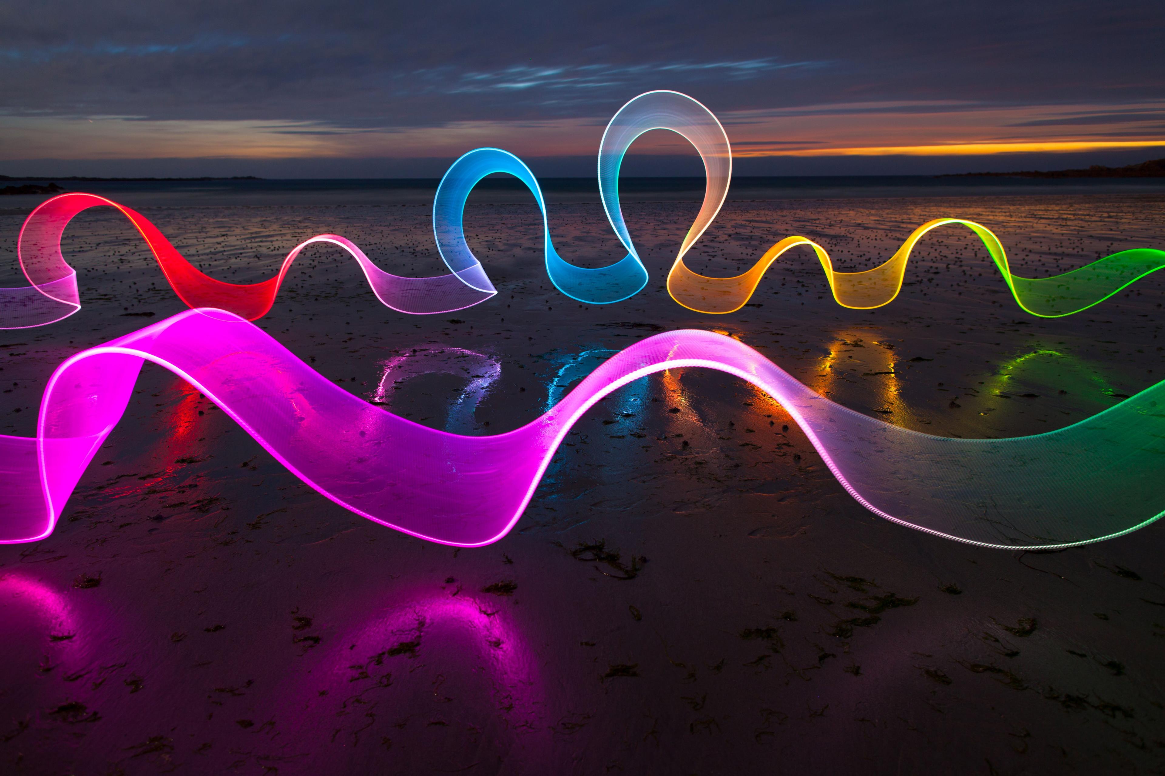 A trail of rainbow light across the whole landscape of the a beach during a sun set. 