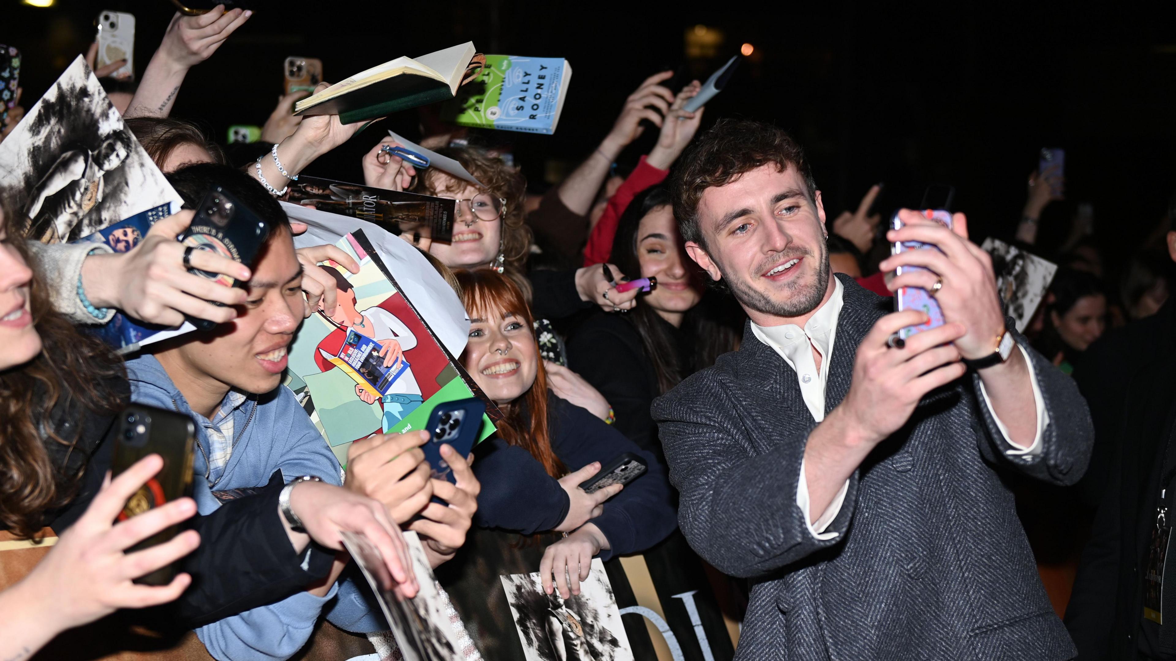 Paul Mescal takes a selfie with fans at the "Gladiator II" Irish premiere at Light House Cinema in Dublin.  He is wearing a white shirt and a grey jacket