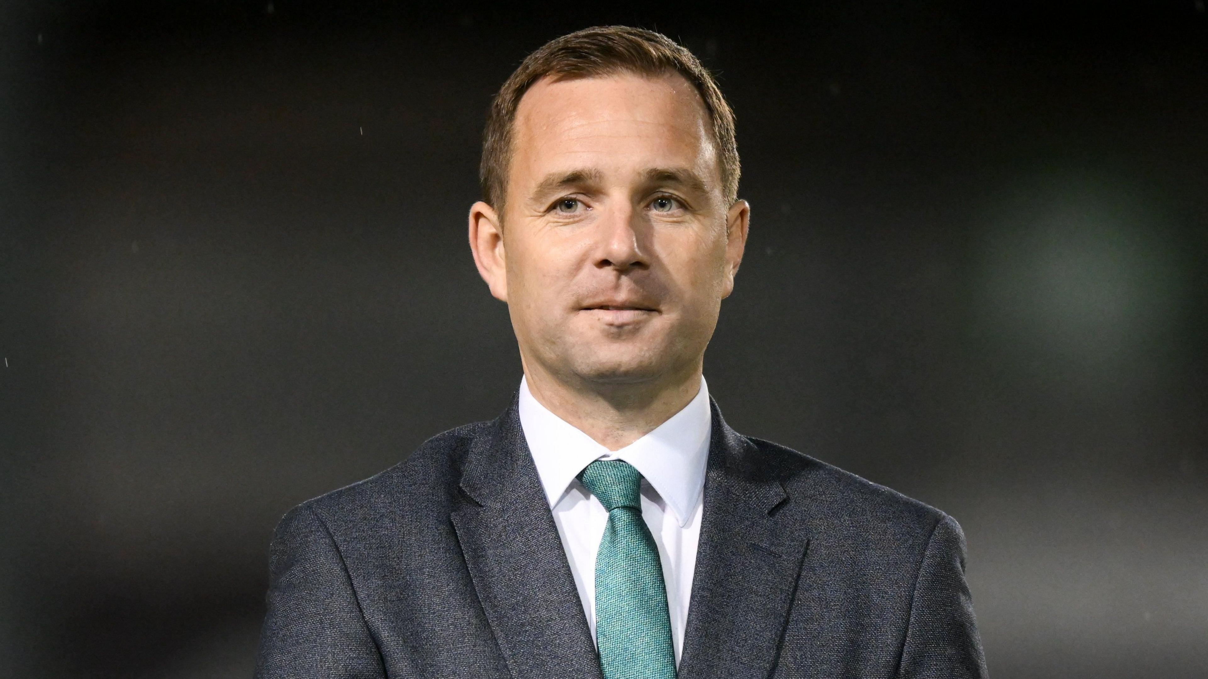 League of Ireland director, Mark Scanlon standing alone wearing a suit and green tie