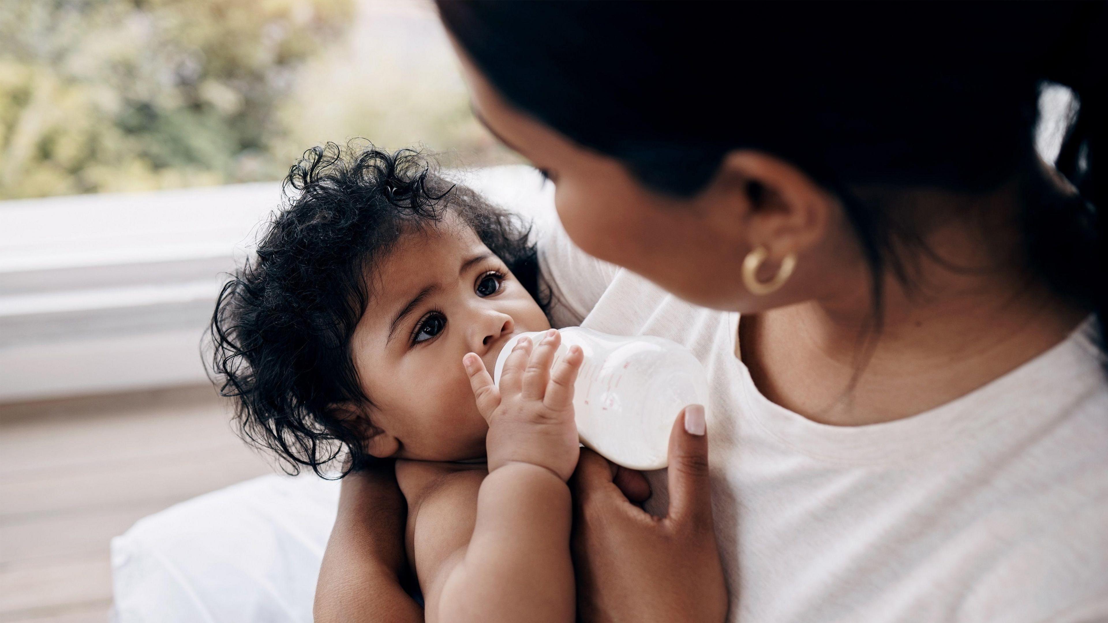 A mother feeding her baby bottled milk