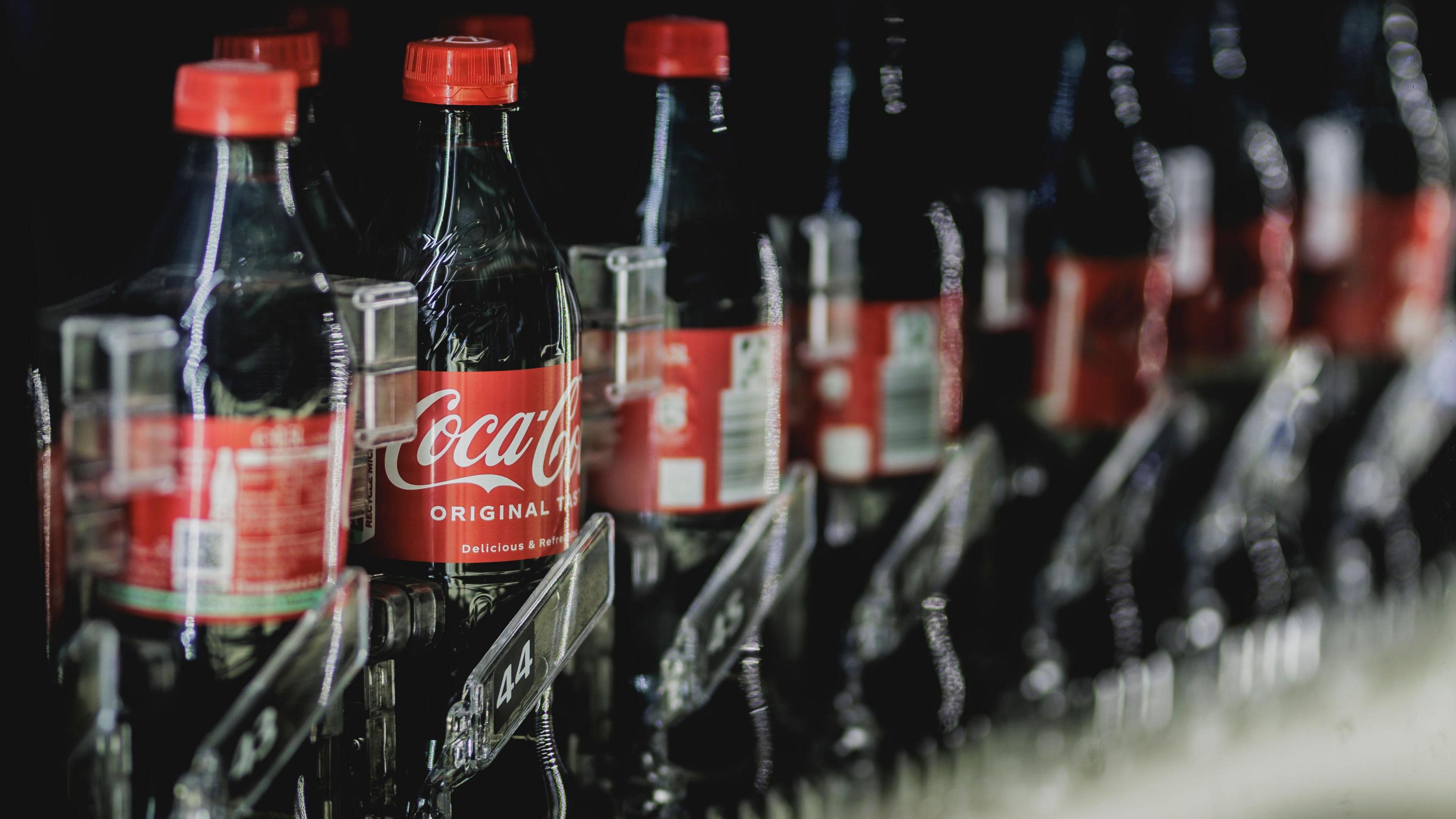 Bottles of Coca Cola pictured in a beverage dispenser.