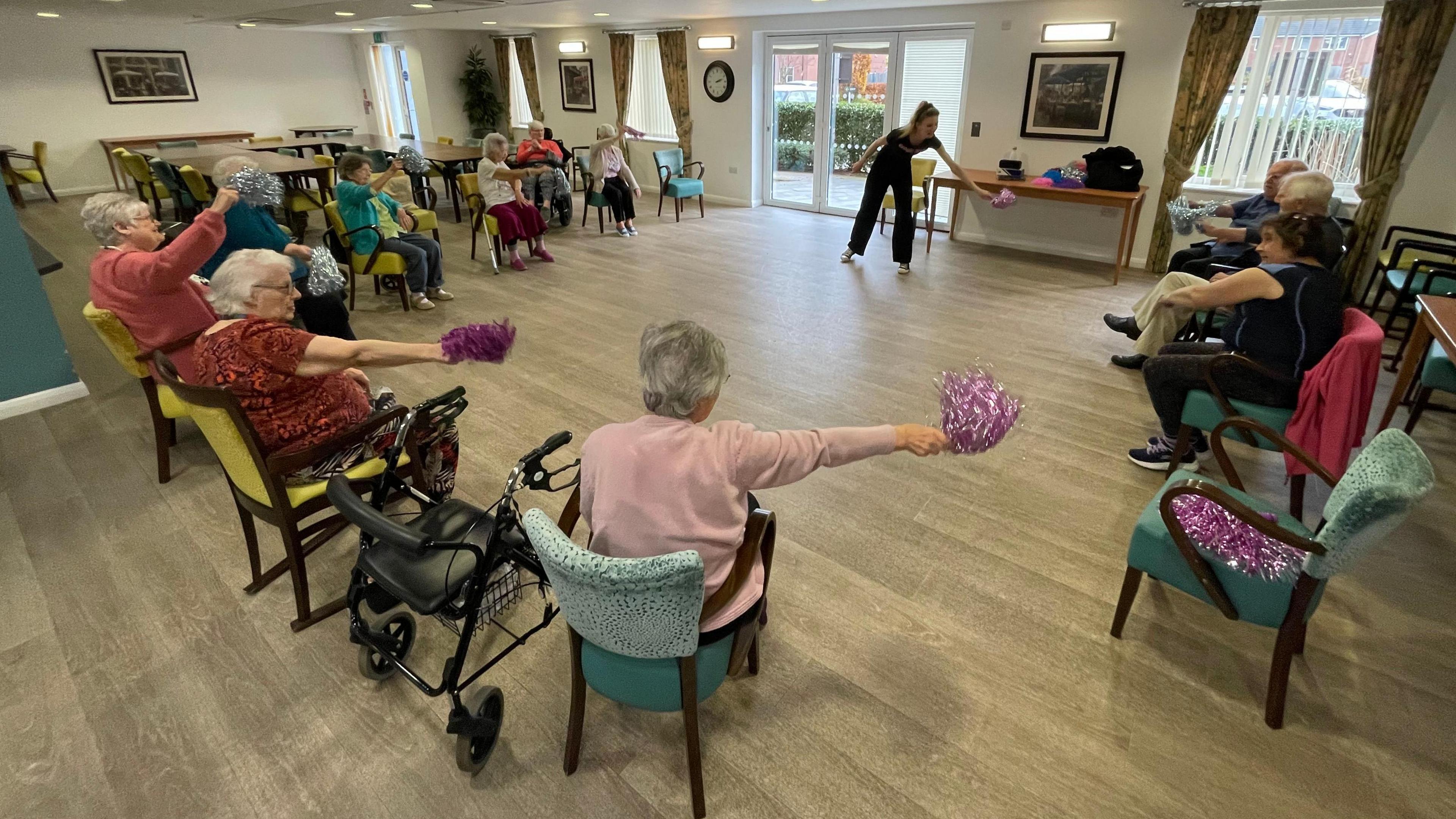 Residents sitting in their chairs and exercising to music