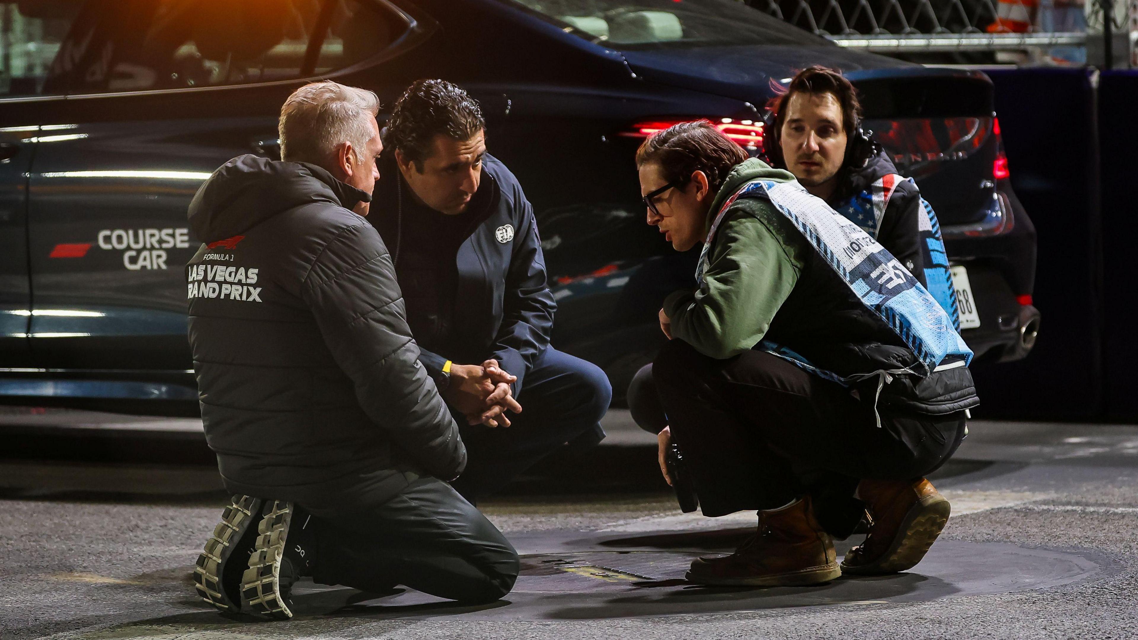 Track officials inspect a manhole cover that came loose after a car passed over it during second practice for the Las Vegas Grand Prix