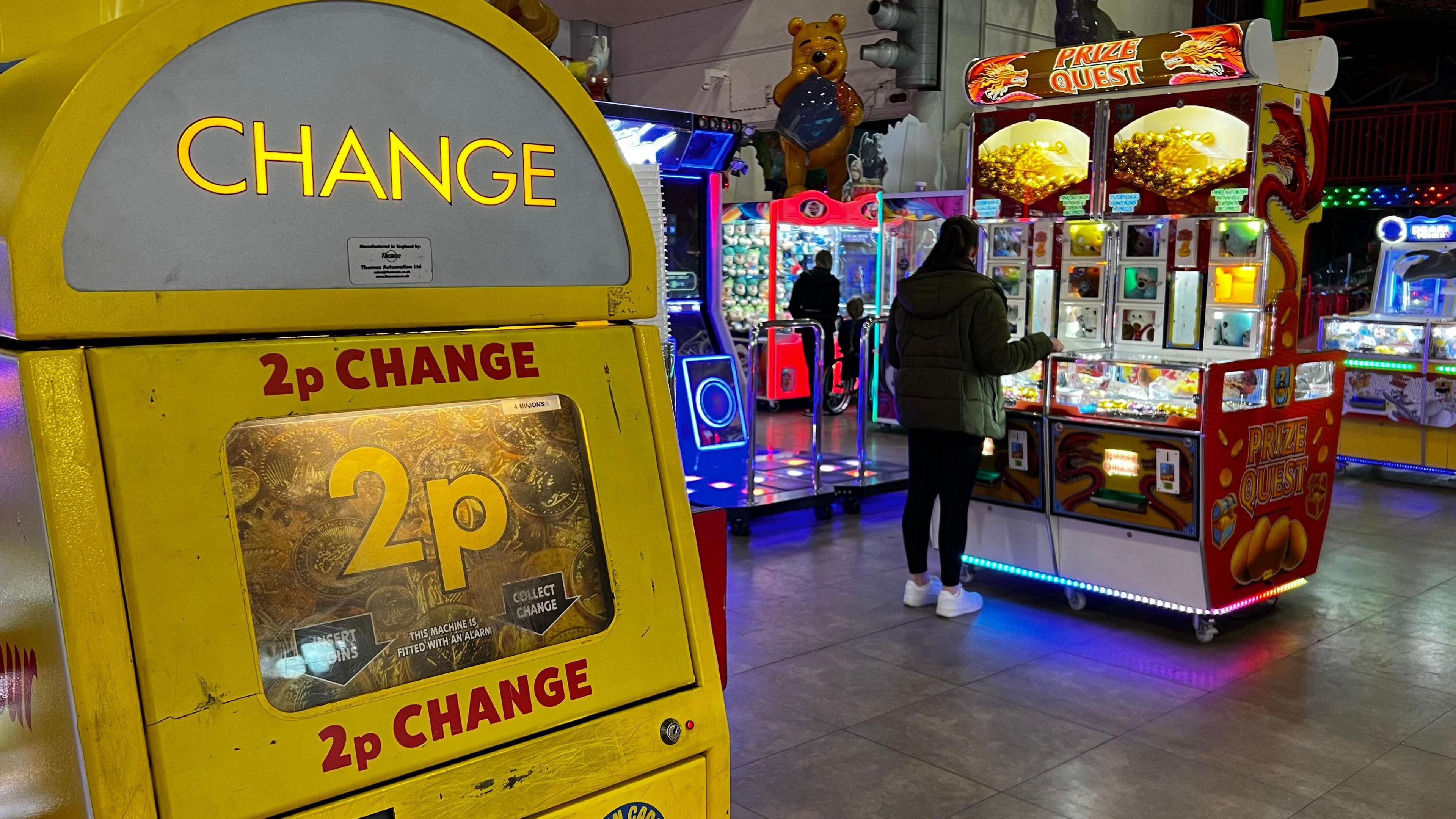 Inside the pavilion of Weston-super-Mare's grand pier showing a person playing one of the arcade games and a two pence change machine.