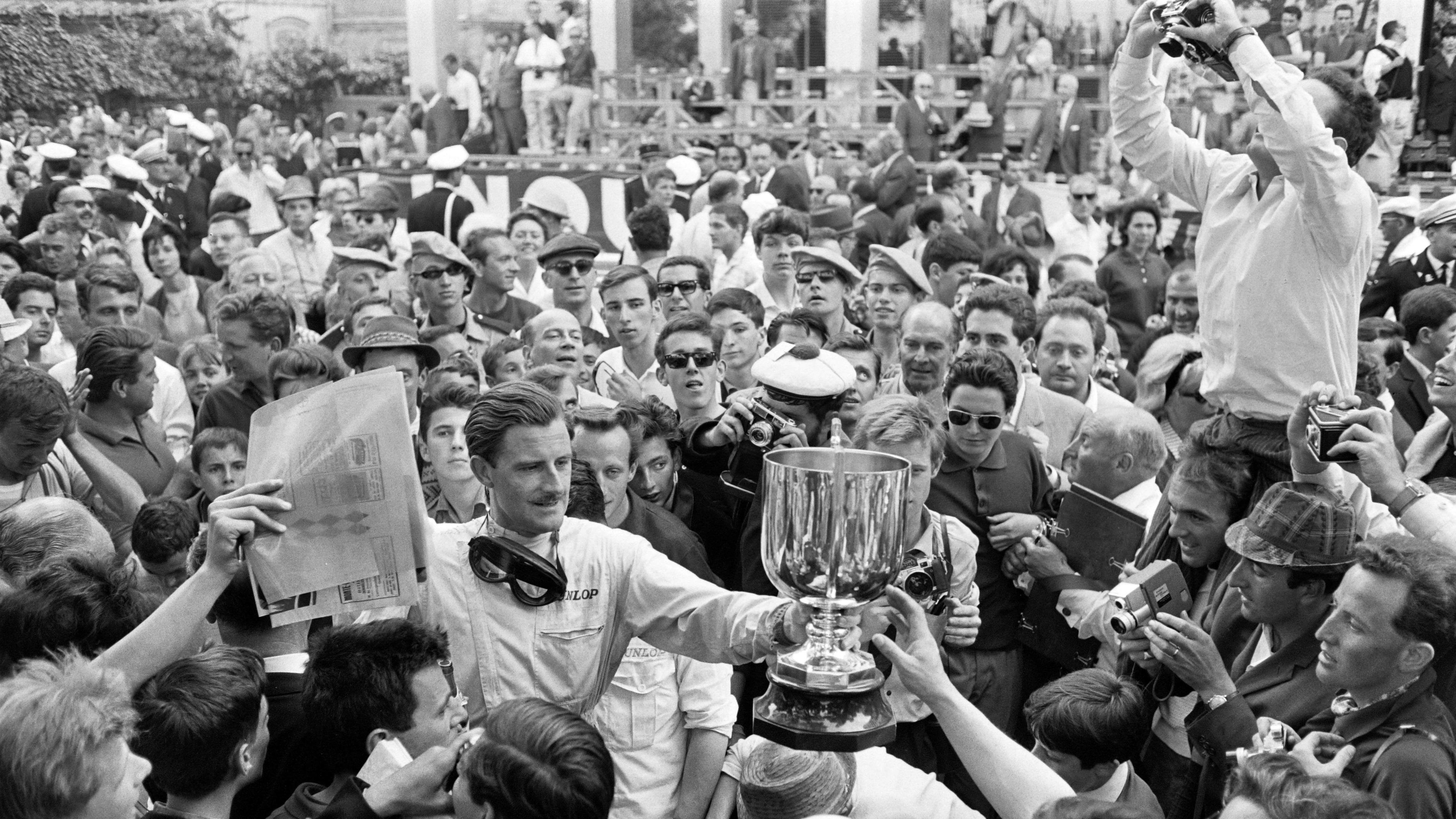Graham Hill holds the winner's trophy as he is surrounded by crowds after his victory in 1963