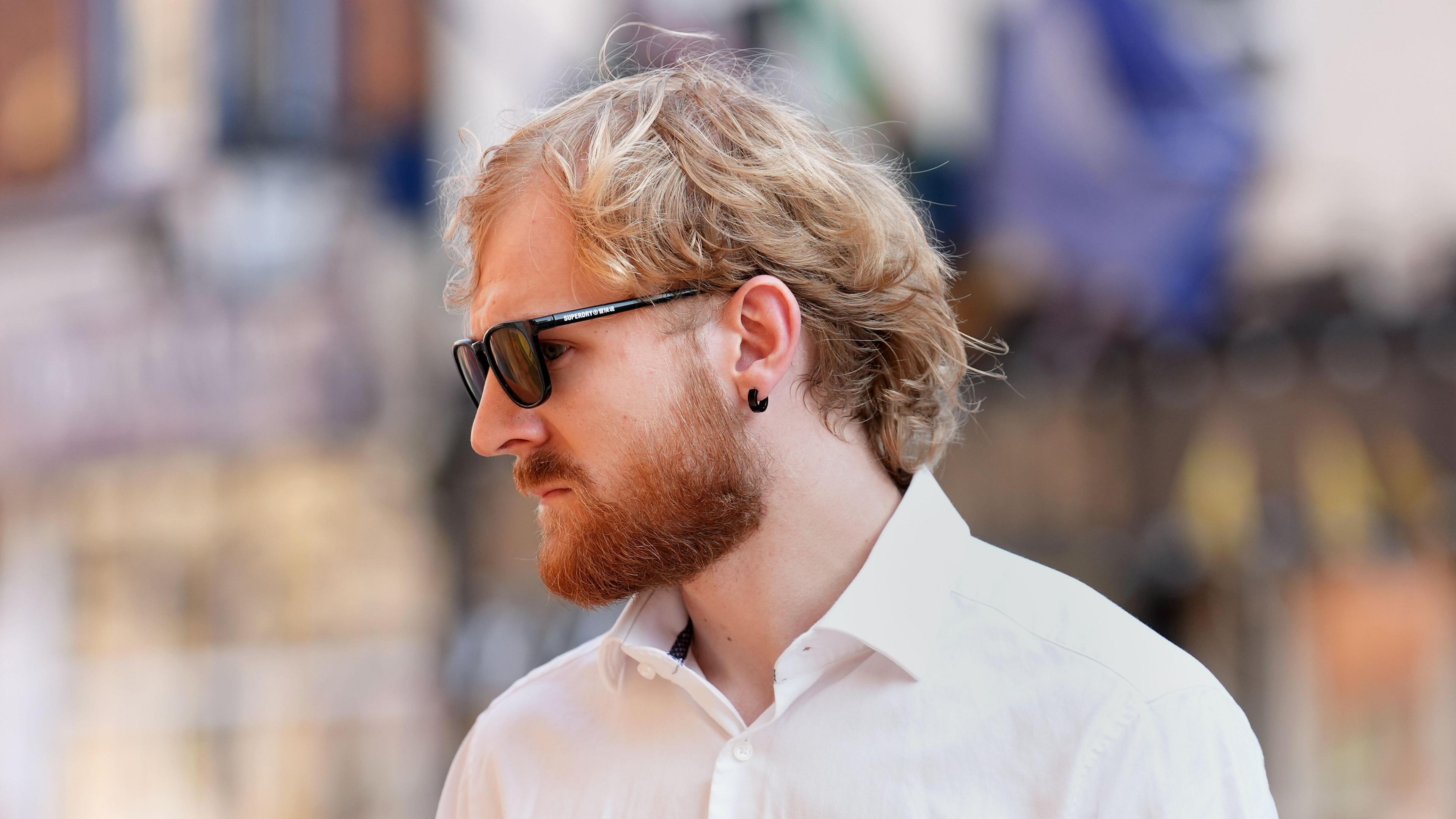A image of a man with blond hair and an earring wearing sunglasses.