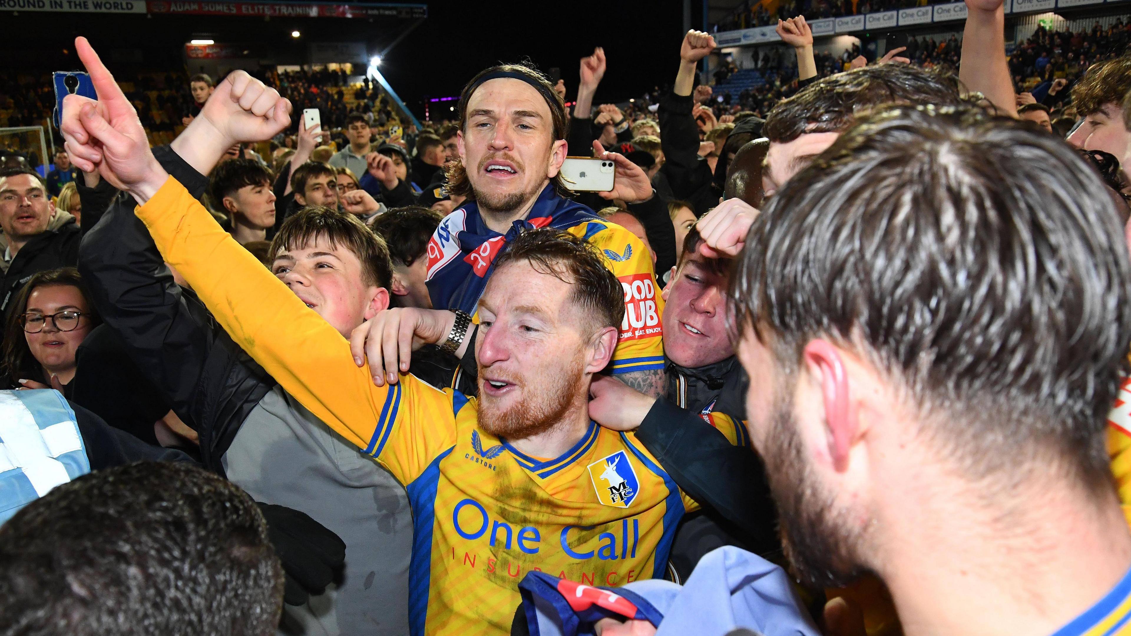 Mansfield Town players celebrated promotion from League Two among fans that ran onto the pitch following their win against Accrington