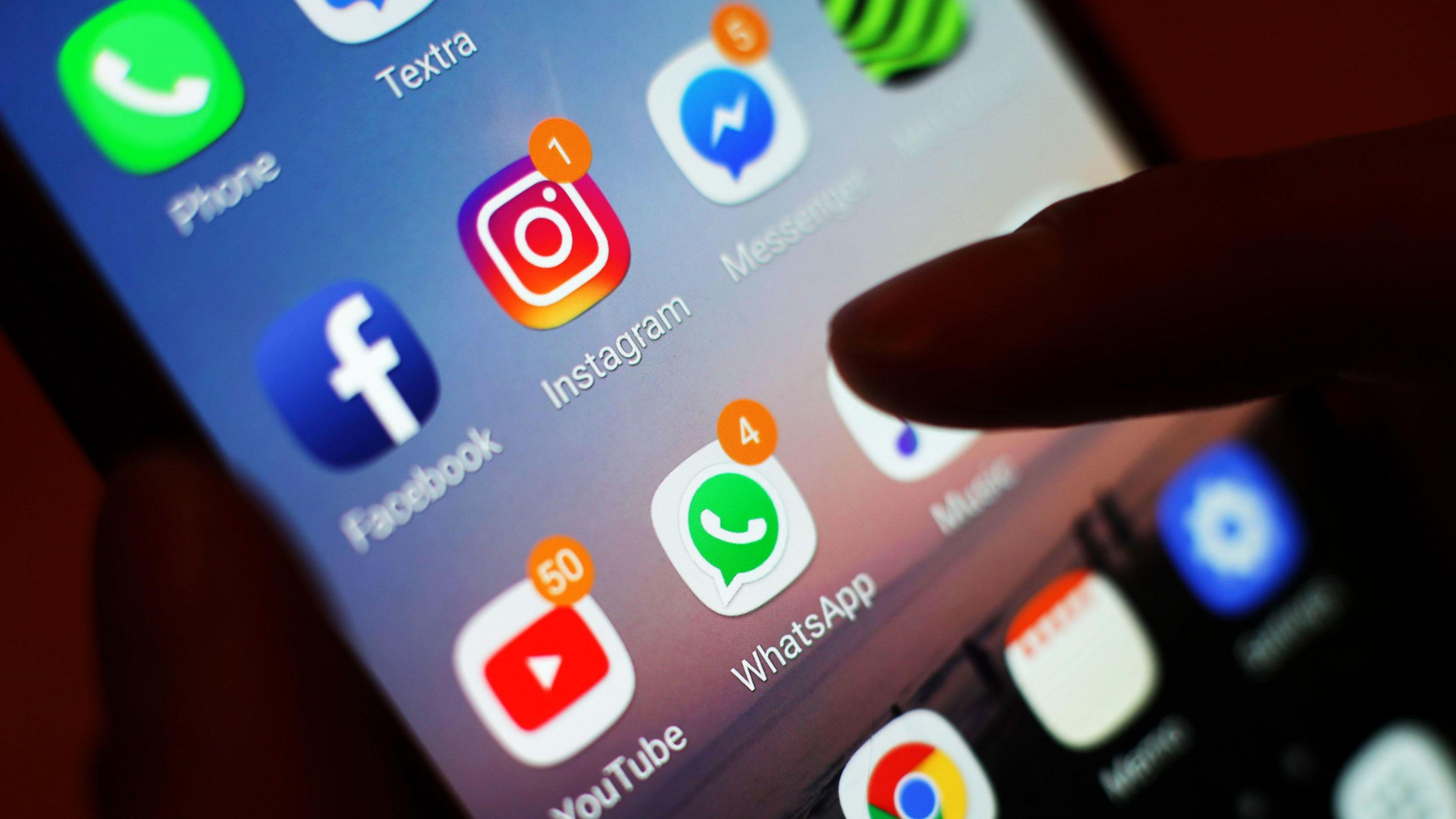 A generic image of a phone and someone about to tap on an app. There are notifications on a number of apps, indicating messages.