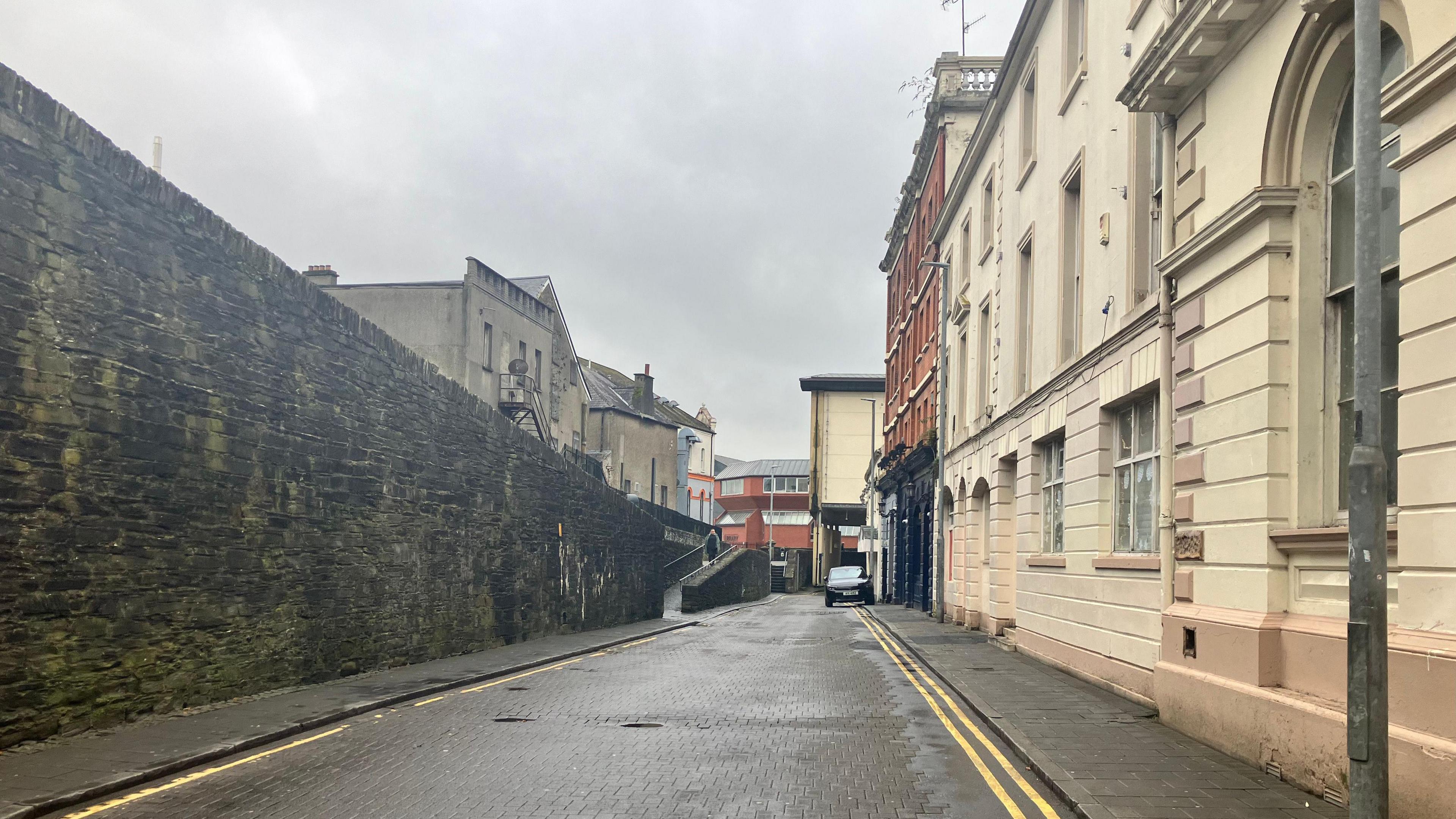 Bank Place in Derry. The City's walls are seen on one side and a row of houses are at the other. 