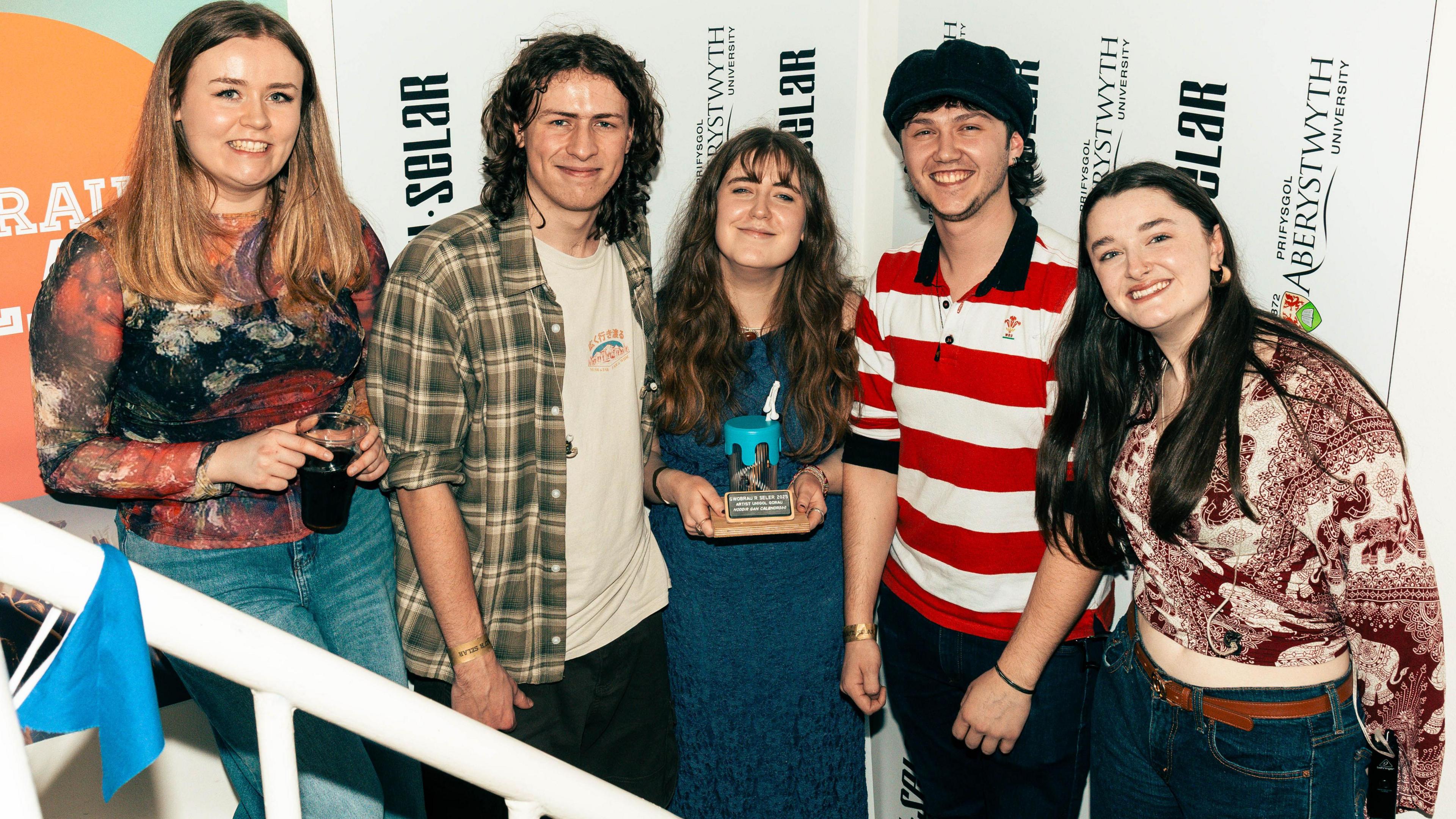 Llun o Buddug yn gafael yn y tlws efo aelodau ei band