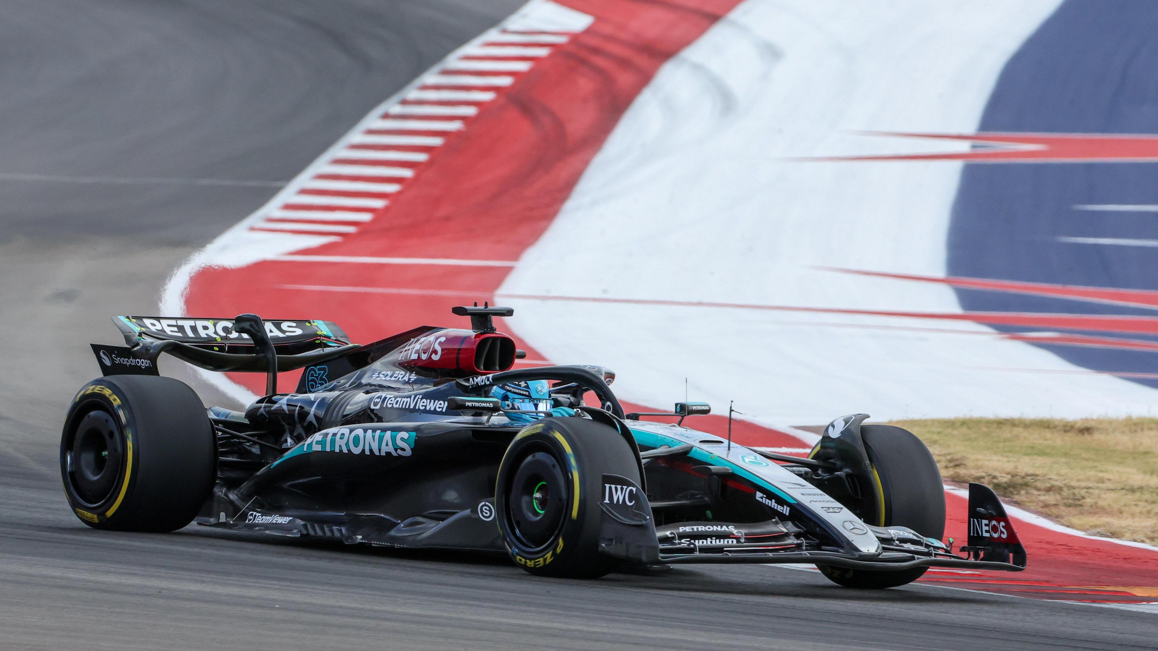 Mercedes' George Russell goes around a corner with the red, white and blue of the US flag painted on the tarmac on the edge of the circuit