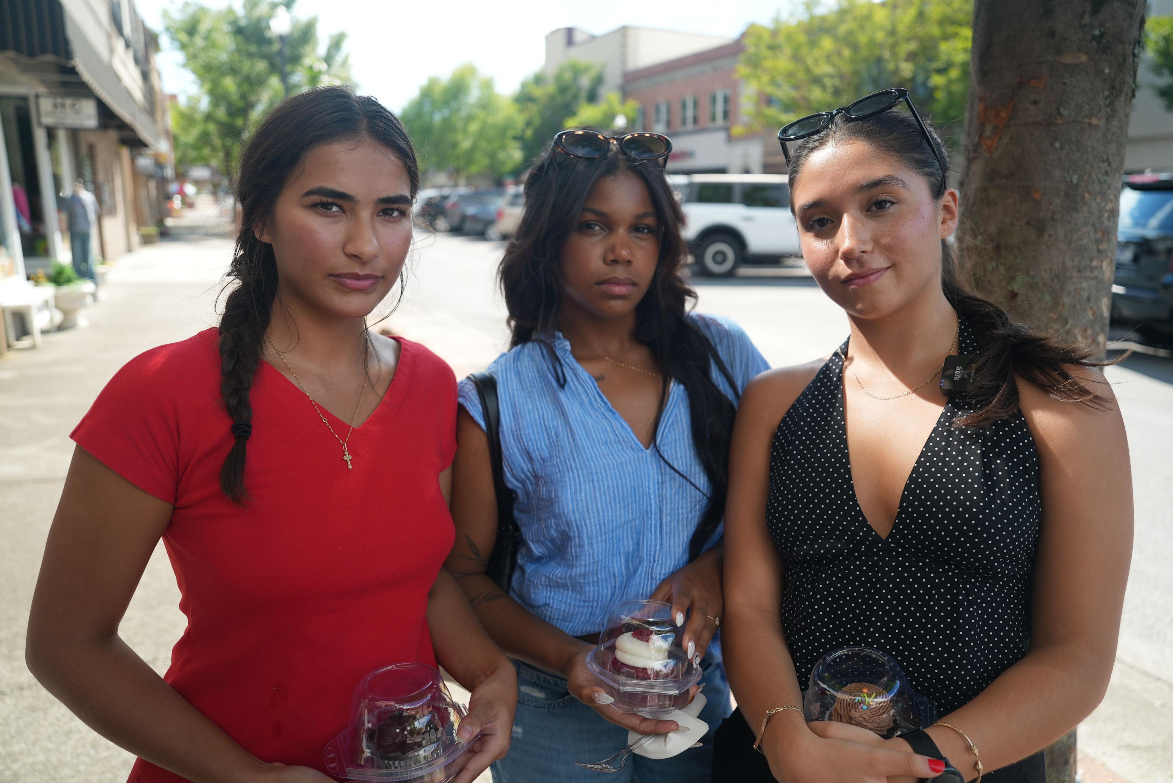 Three 21-year-old women stand holding cupcakes just purchased in a shop on one of Kingsport's main streets downtown. One wears a red V-neck top, cross necklace and her long, dark hair in a braid. The friend next to her wears sunglasses atop her head and a blue v-neck top above jeans. The third, her hair in a ponytail, wears a black halter top and sunglasses atop her head
