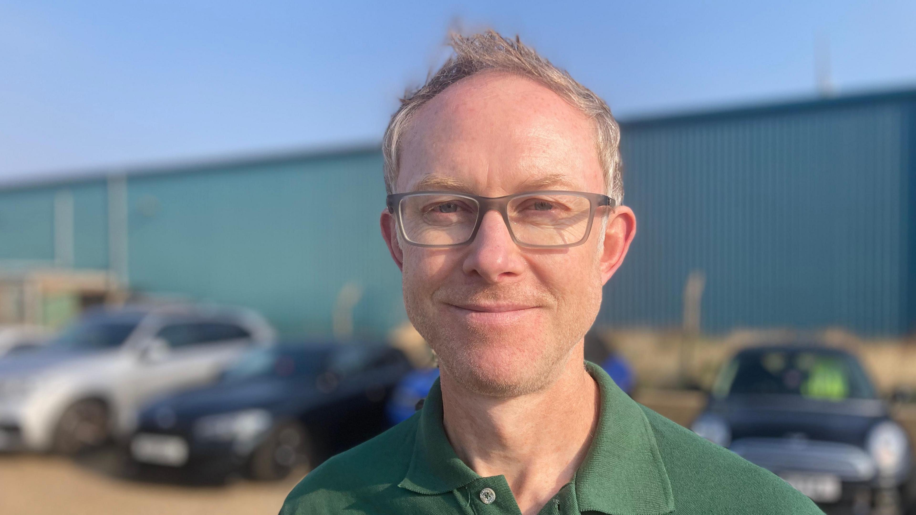 Ross Ovens of Scottish Power is pictured smiling to camera. He is wearing a green polo T-shirt with the Scottish Power logo embroidered on it. He has glasses and light coloured hair.