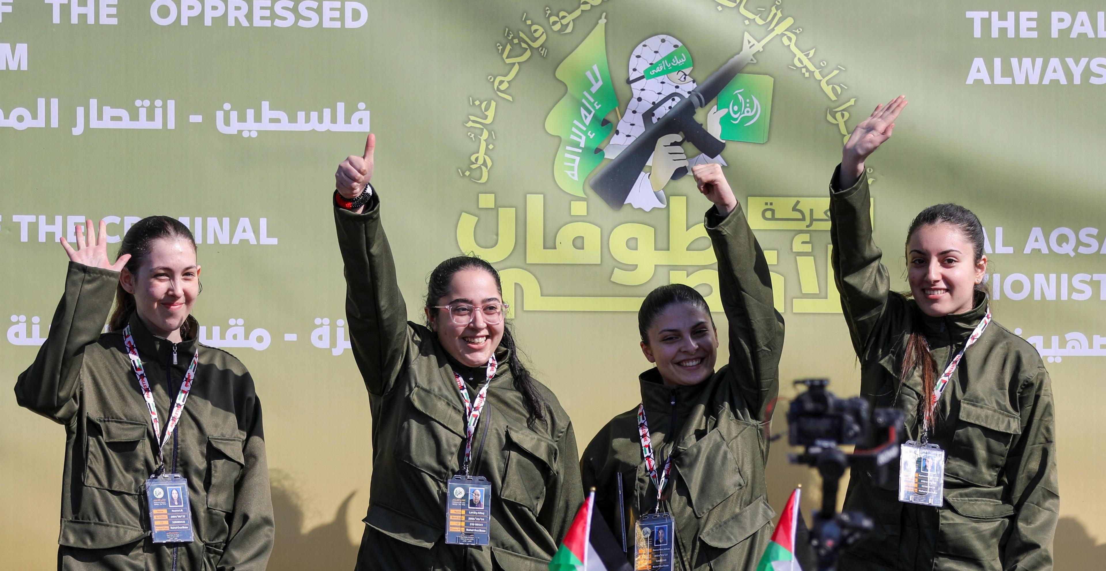 Naama Levy, Liri Albag, Daniella Gilboa and Karina Ariev wearing khaki clothes, stand on a stage and wave to a crowd.