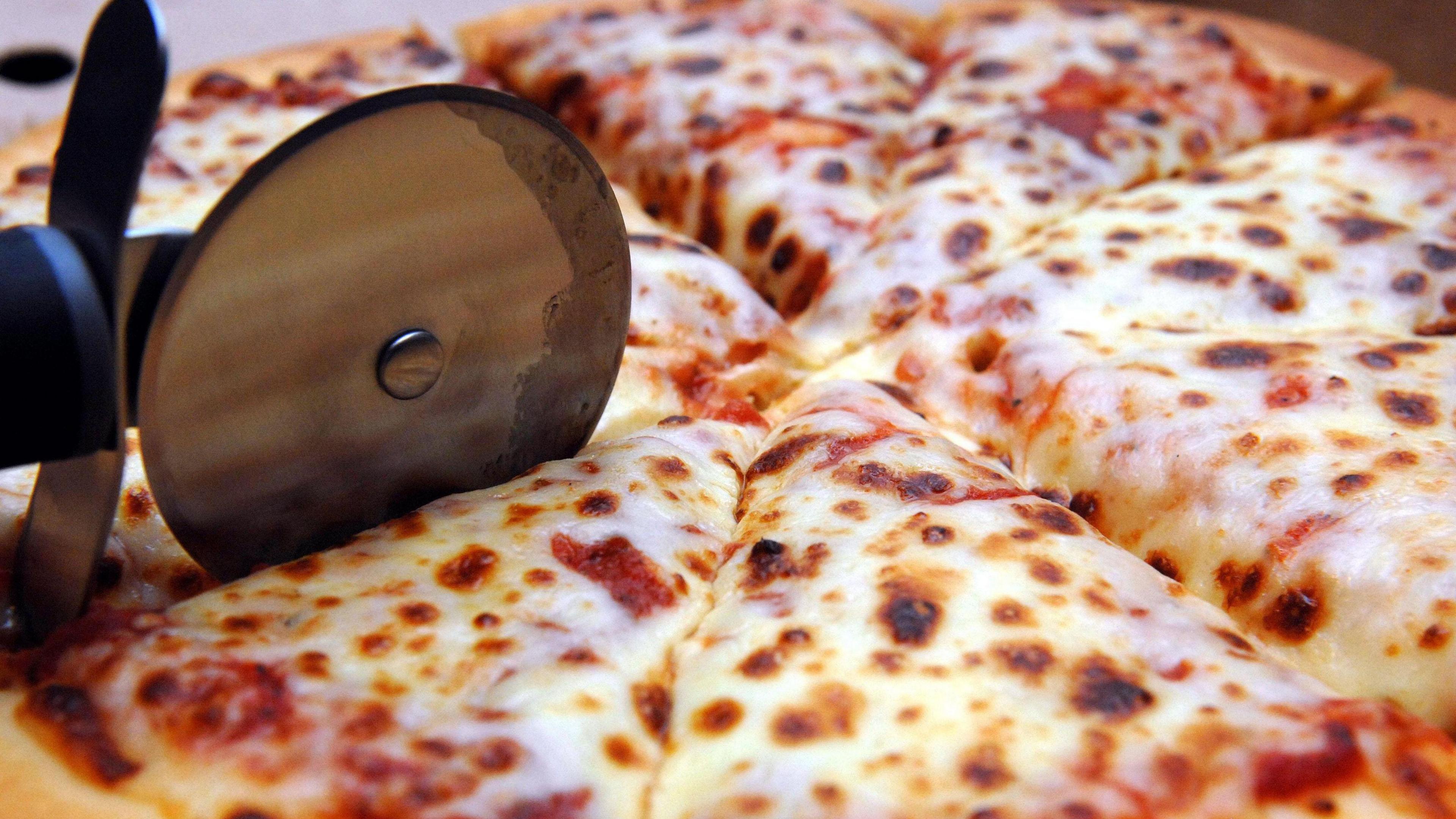 Close-up of a pizza wheel cutting a pizza into several slices