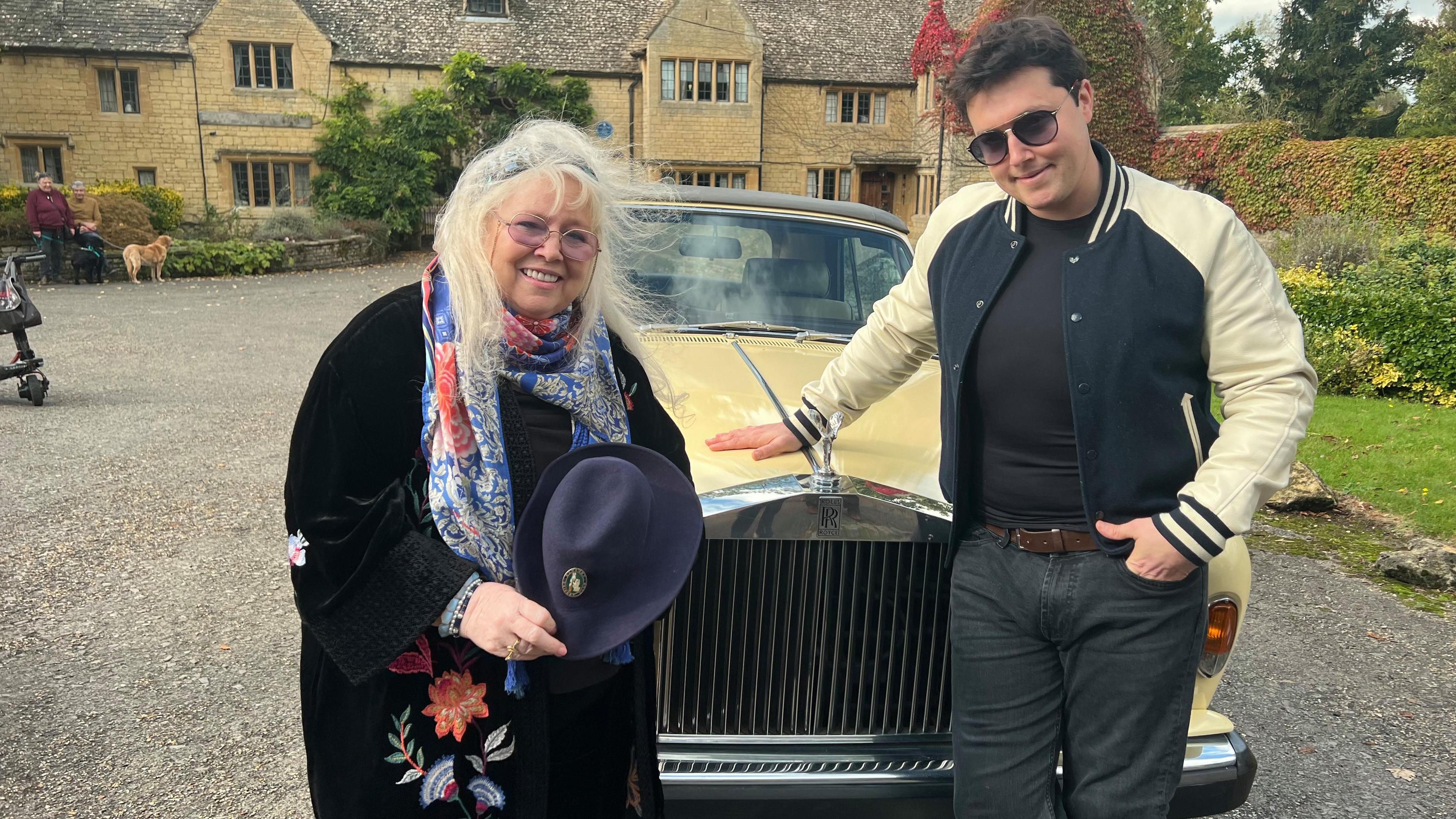 Dwina and RJ in front of a yellow Rolls Royce. It is in front of Robin Gibb's large house, which has a blue plaque.